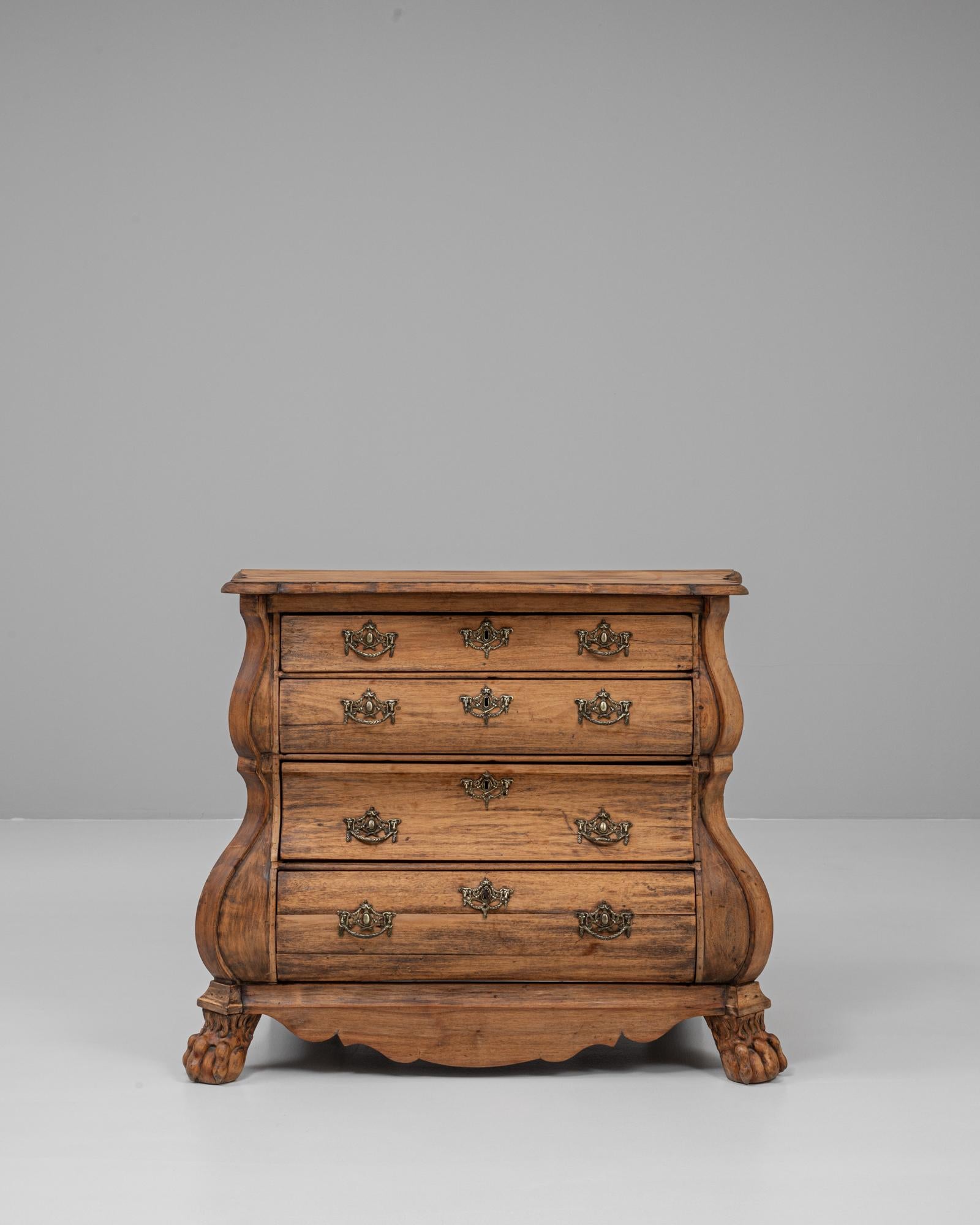 Questa cassettiera olandese in legno Bombe del 1820 è un esempio straordinario di artigianato europeo del XIX secolo, che mostra le curve eleganti e il design robusto tipico della forma Bombe. Realizzata in legno ricco di venature e con una patina