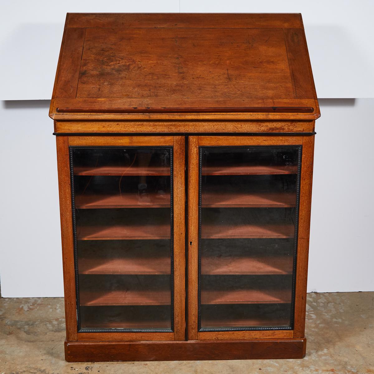 1820s English William IV mahogany portfolio cabinet. A William IV portfolio cabinet in mahogany with glazed door and adjustable shelves. The front and back beveled glazed doors are fitted with carved moldings. Cabinet sides with brass pulls open to