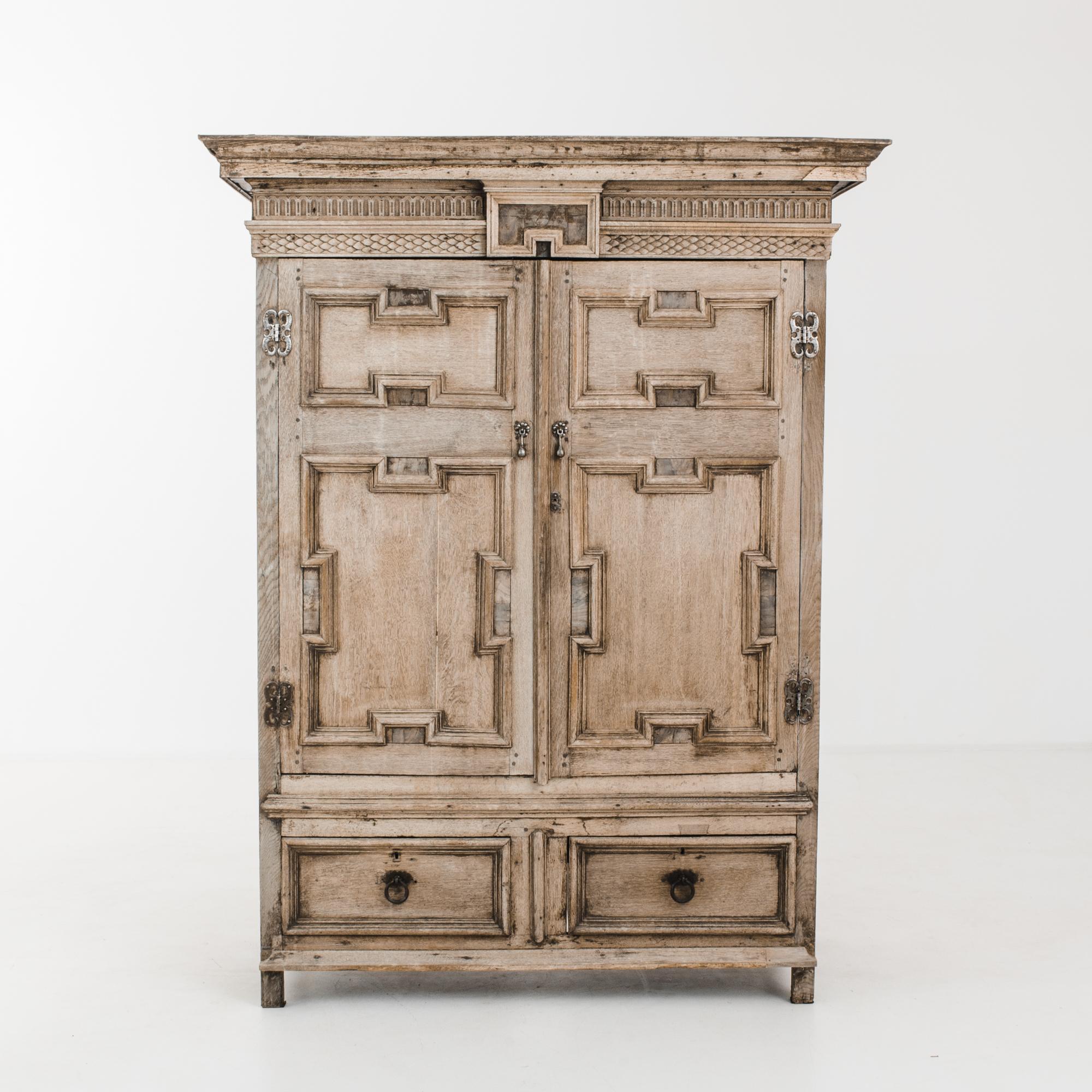 This bleached oak cabinet was made in Europe, circa 1820. Crafted by artisans, the refined carvings of arched fluting and scales below the crown molding demonstrate the skill of traditional woodworking. The cabinet features geometric paneling,