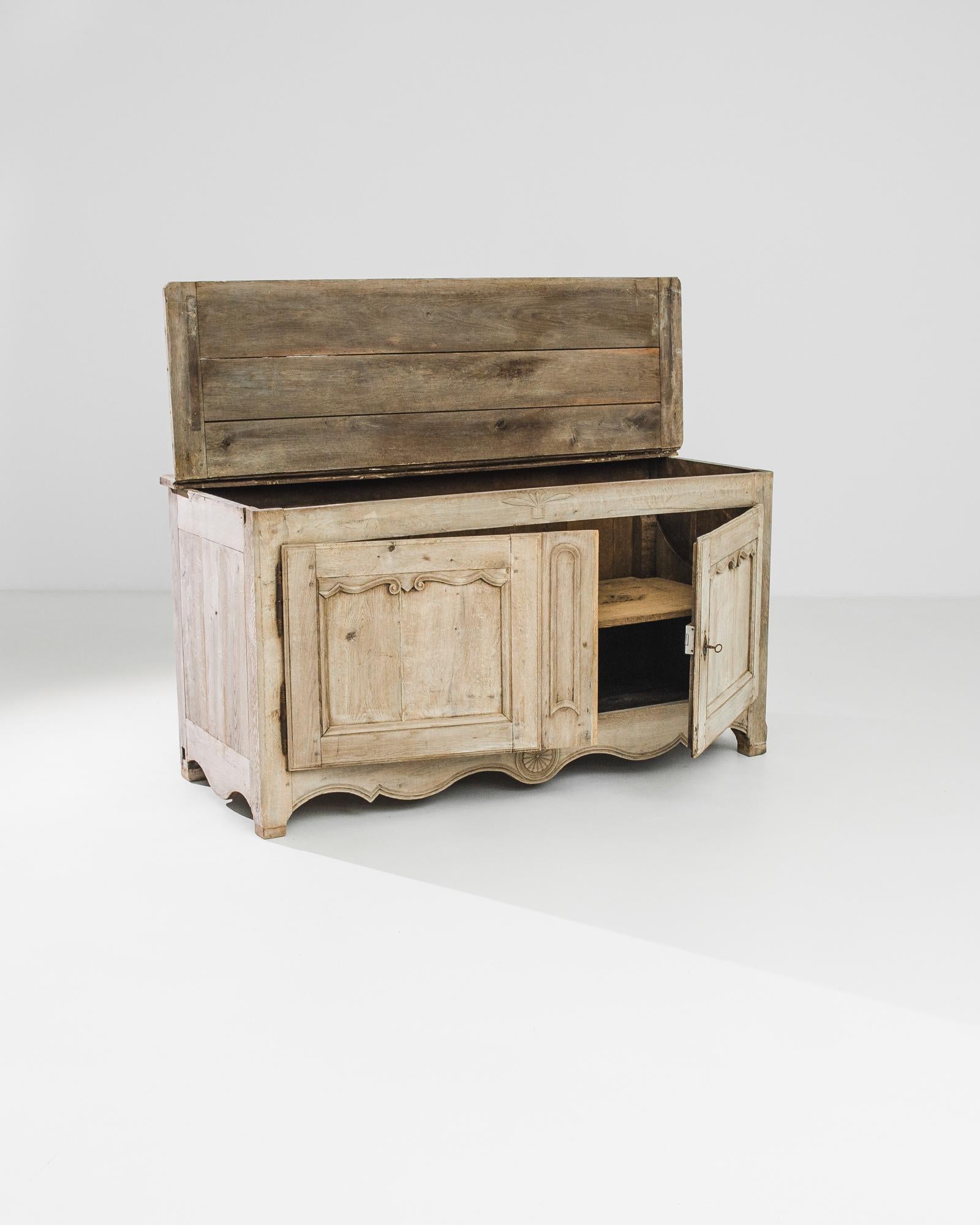 Un buffet in rovere sbiancato proveniente dalla Francia, prodotto intorno al 1820. Con una facciata finemente incisa, questo buffet unico presenta un mobile a doppia anta con due ripiani e un coperchio a ribalta. Grazie alla funzione di baule in