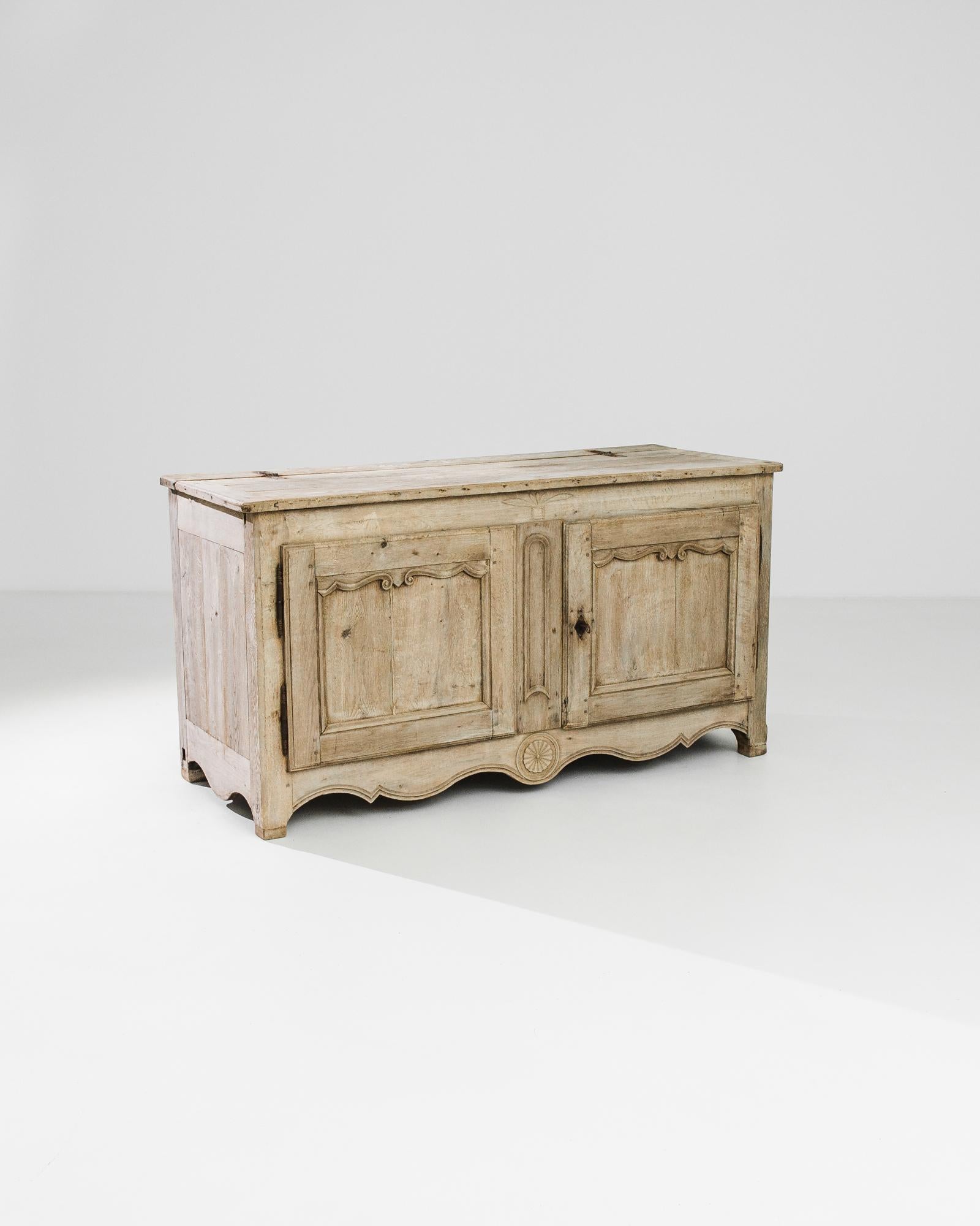 A bleached oak buffet from France, produced circa 1820. With a fine facade fairly etched, this unique buffet features a double door cabinet of two shelves, and swing-top lid. Moonlighting as a top-accessible wooden trunk means this multifaceted