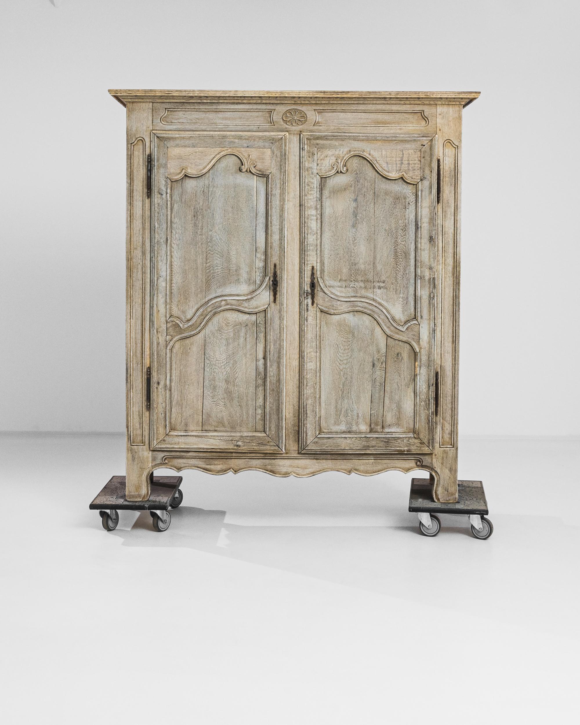Transform your space with the timeless elegance of this 1820s French Bleached Oak Cabinet. Adorned with intricately carved designs on the doors and surrounding areas, this cabinet exudes sophistication and charm. Its scalloped apron adds a touch of