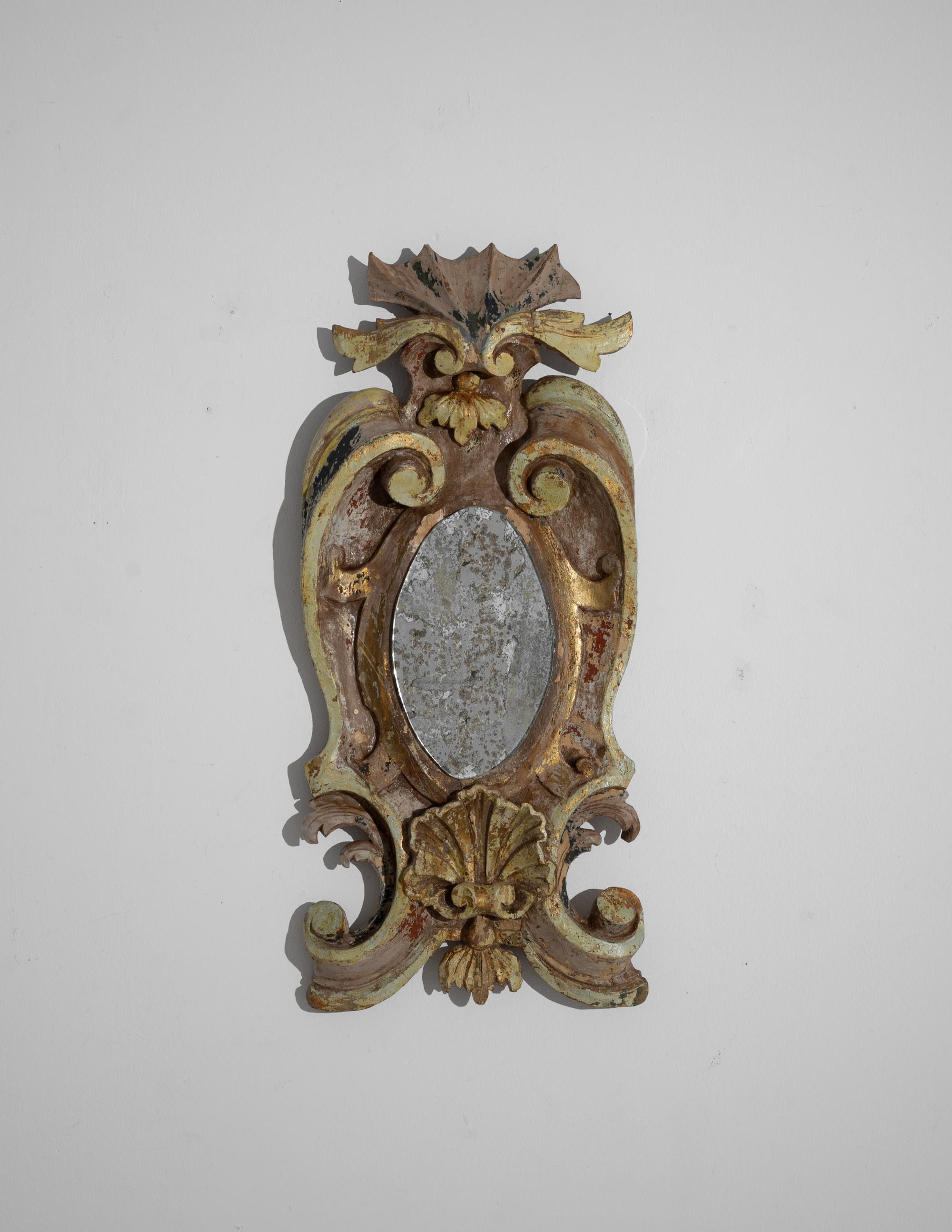 This antique wooden mirror was produced in France, circa 1820. A grandiose mirror with a baroque influence, garnished with scrolled foliage and luxuriant ornamentations. The ribbons and festoons are completed by a central shell-shaped carved piece