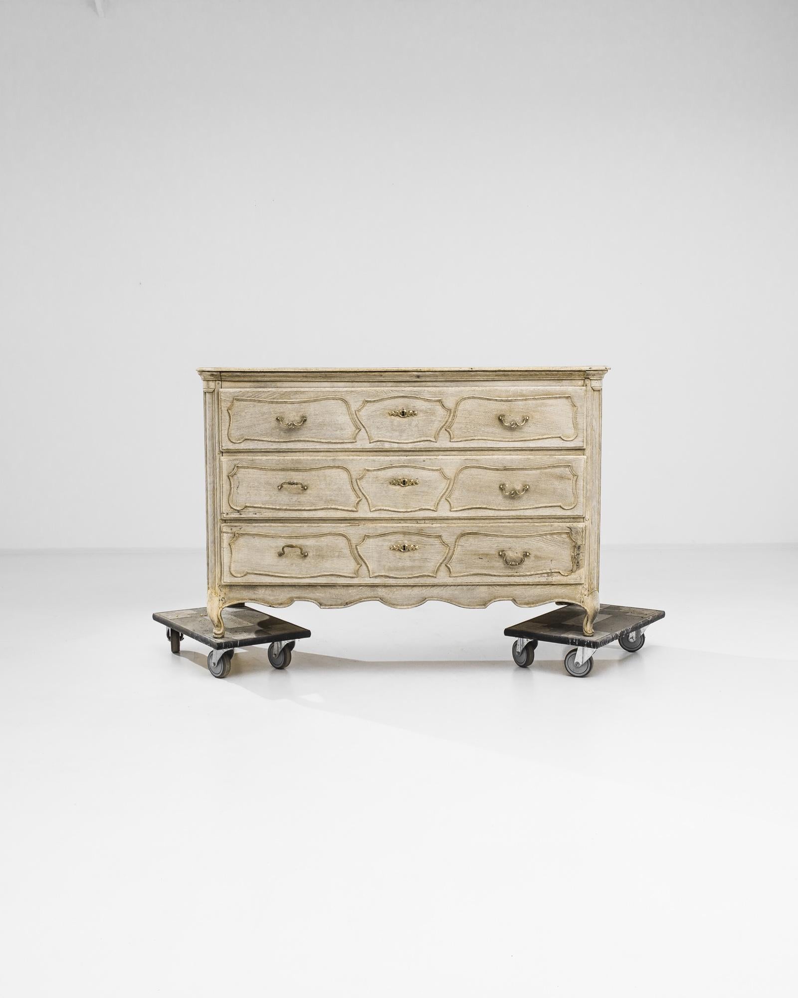 Carved paneling and the pale primrose tone of the restored wood give this oak chest of drawers an air of enchantment. Built in France in the 1820s, the serpentine lines of the drawer panels captivate the eye, lending the upright cabinet a sensuous