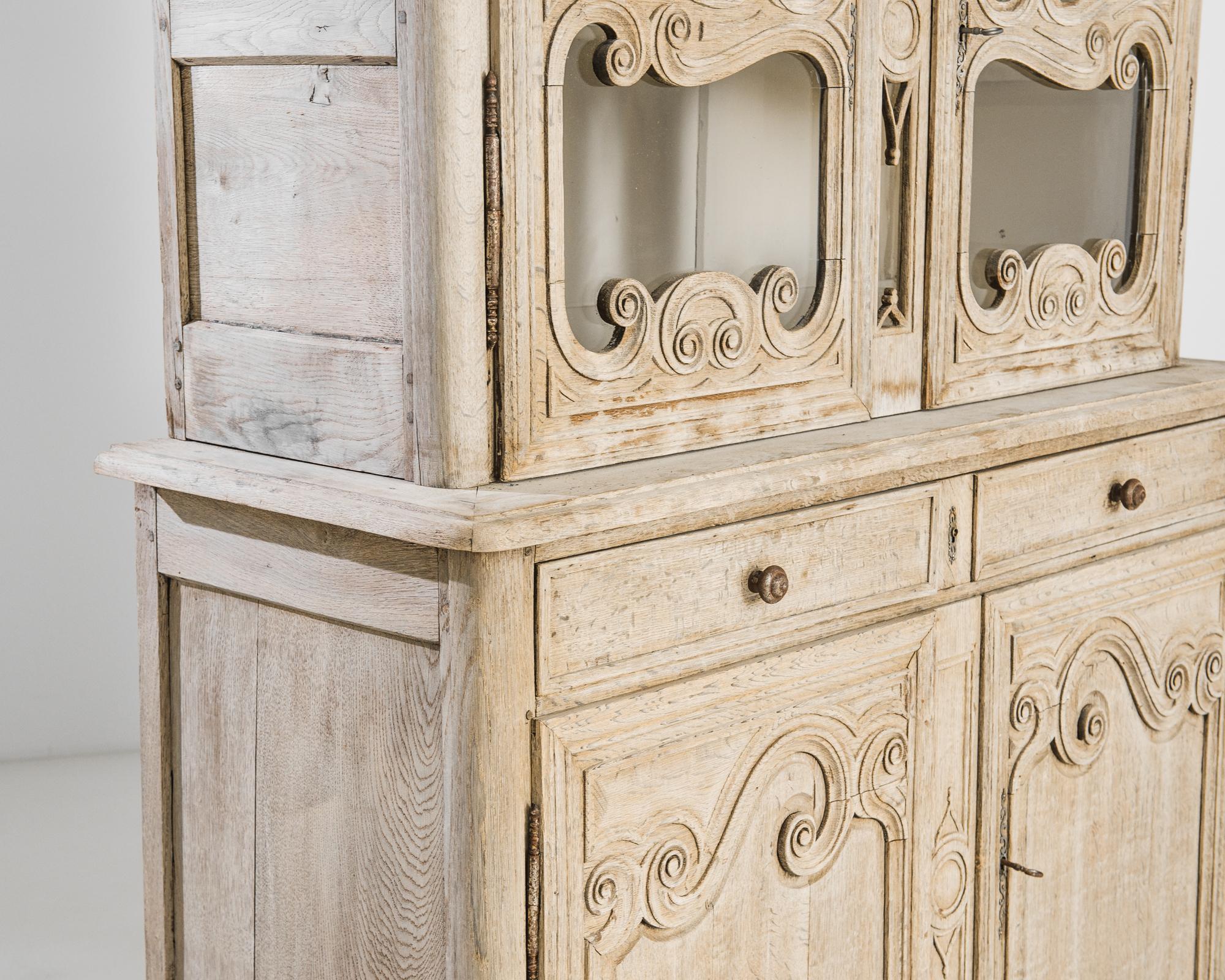 Scrolled moldings lend this statuesque vitrine a light-footed elegance. Built in France in the 1820s, a series of spirals give the panels of the drawers and the borders of the paned windows a vivacious fluidity. The wood has been restored to reveal