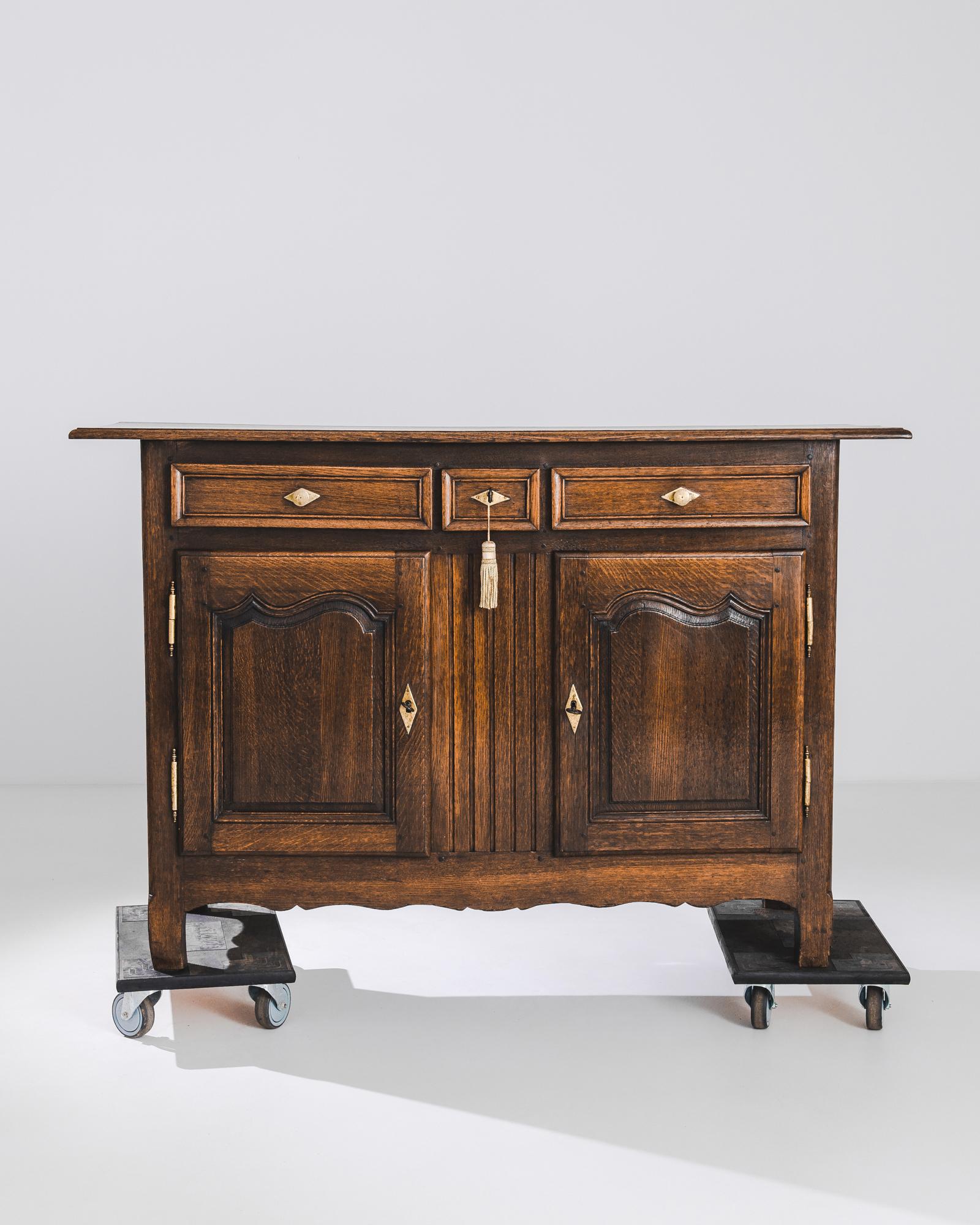 A wooden buffet from 1820s France. The tawny color and deep shine of the original patina make a warm, dignified impression; the lively curves of the door panelling and scalloped apron lend a sense of fluidity to the upright case. Gilded,