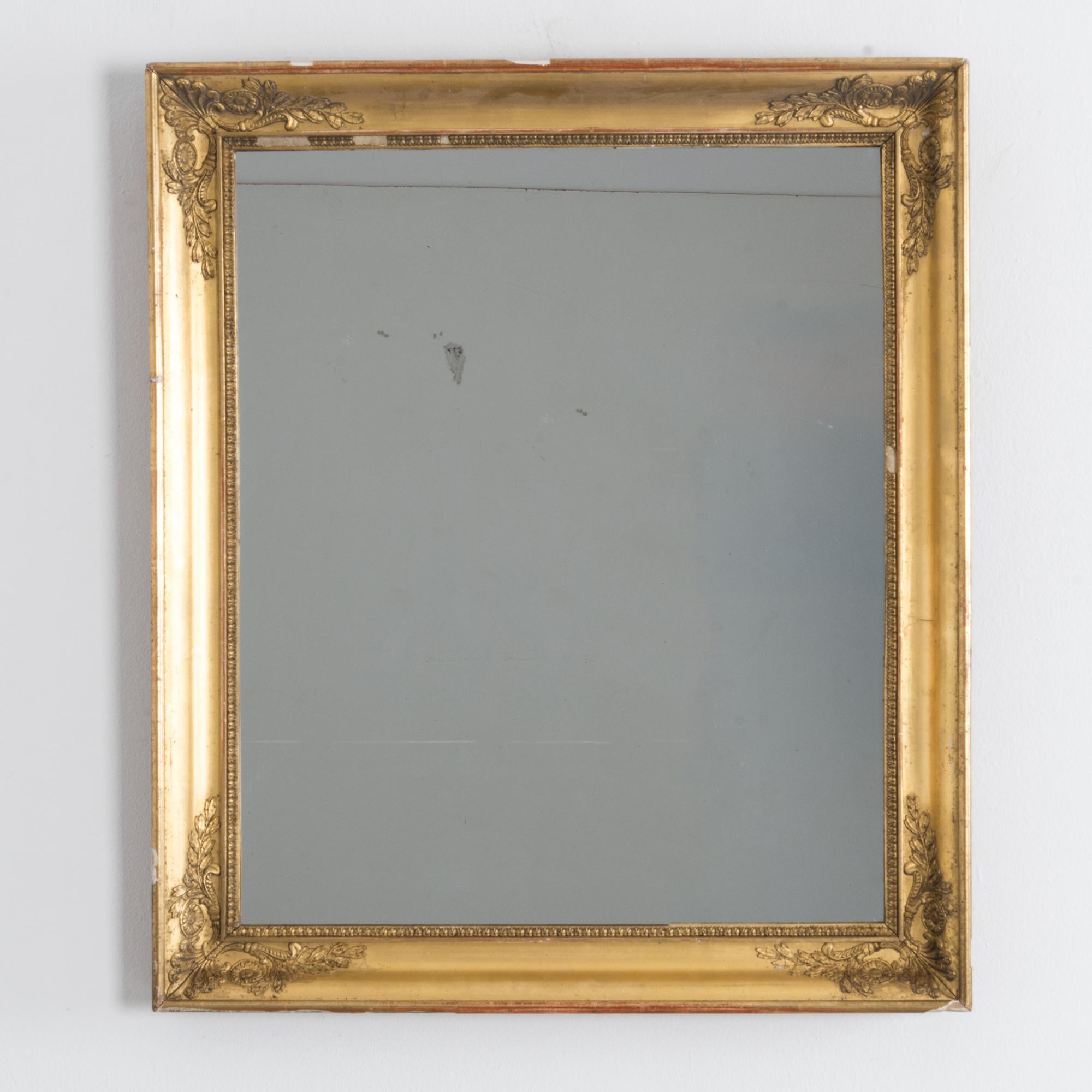 Questo sofisticato specchio in legno presenta un'intramontabile finitura dorata e una cornice rettangolare ornata da delicati decori floreali e di foglie ad ogni angolo. Gli intricati dettagli delle perline lungo il bordo interno completano gli