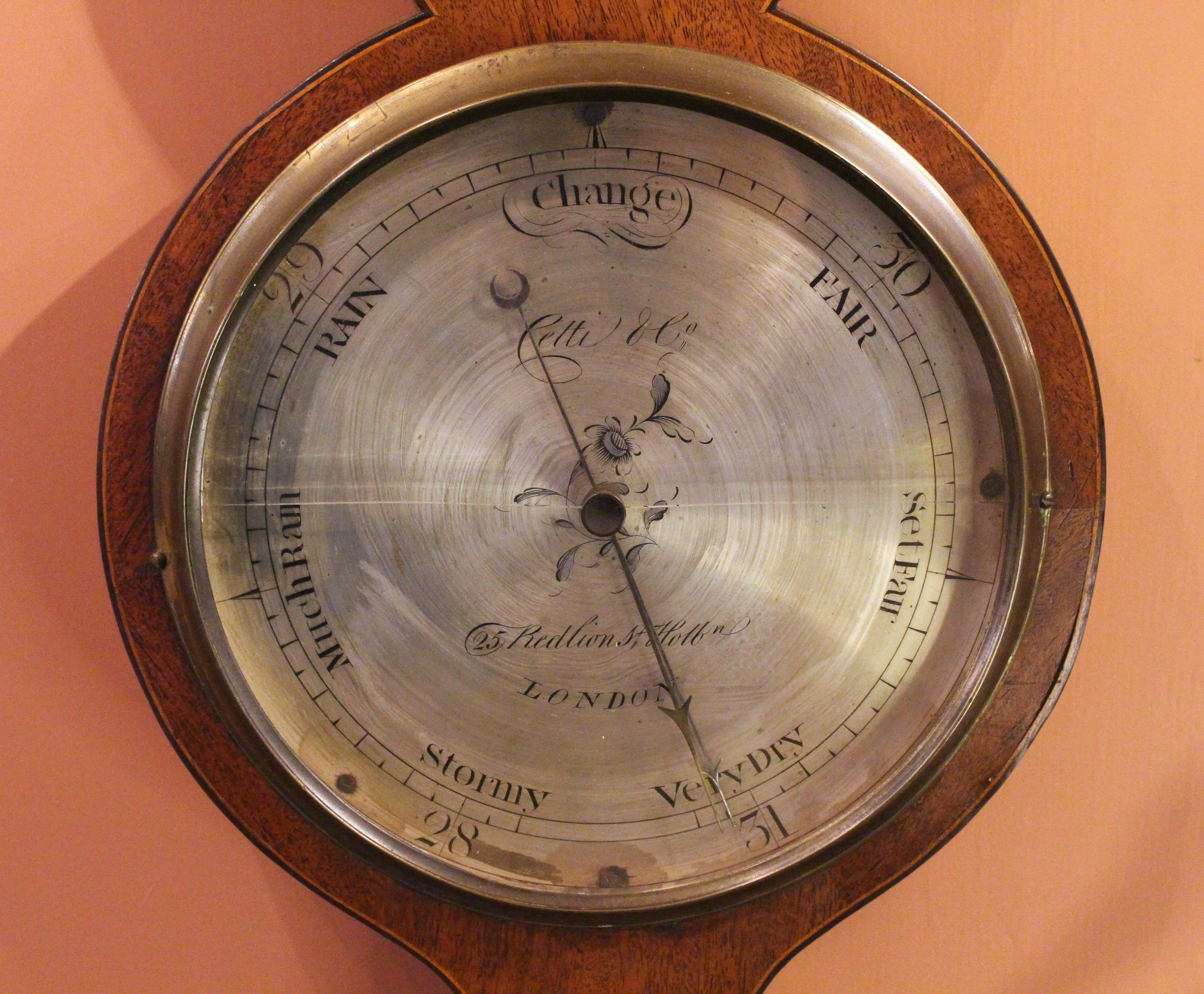 1816-1829 barometer by Cetti & Co, 25 Red Lion St., Holburn, London. Mahogany with conch shell & rosette inlays. George III period. Not currently working. The original finial is fire gilt. Broken arch pediment is original. Provenance from a 1957