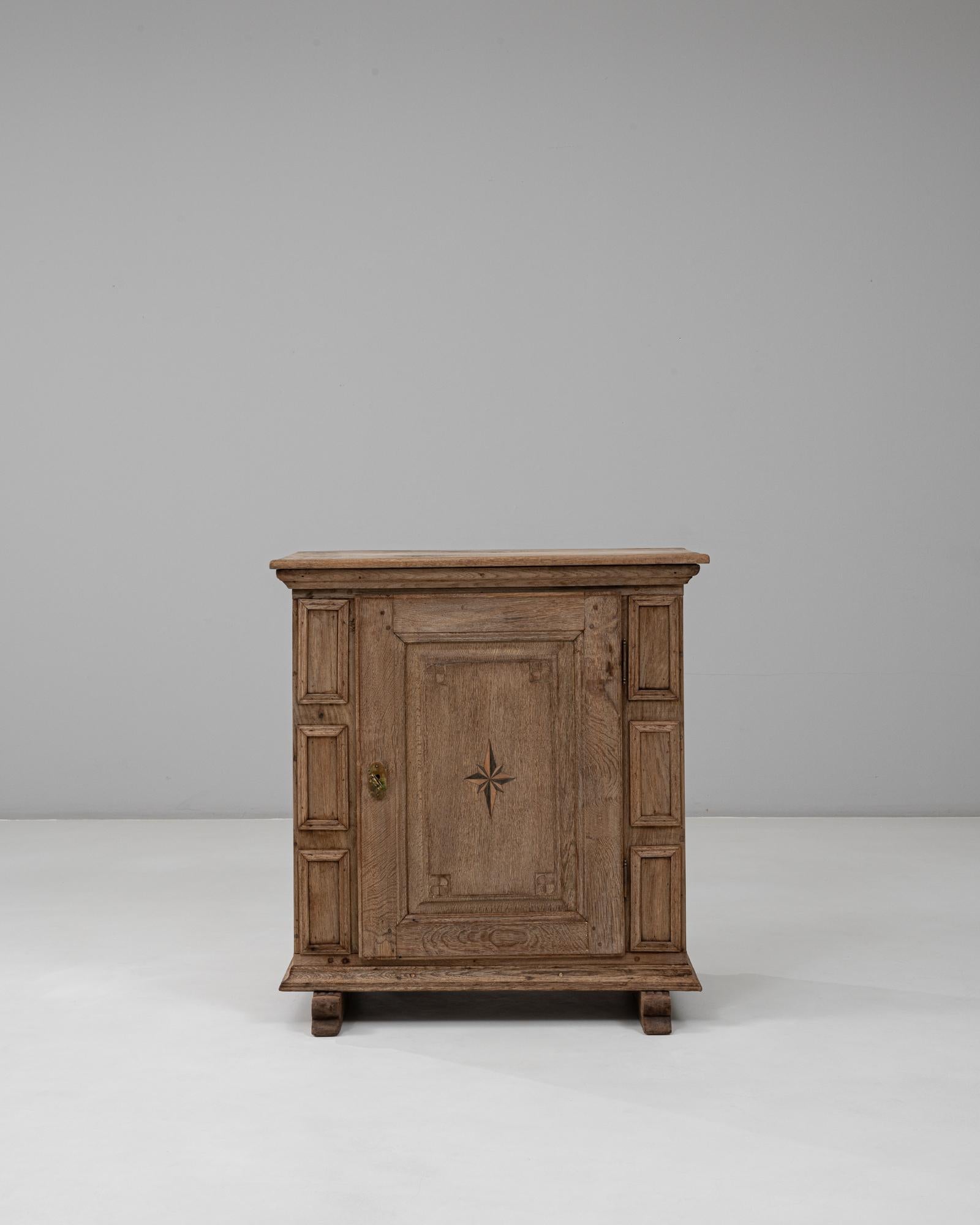 Ce buffet alpin allemand du début du XIXe siècle présente une exécution exceptionnelle en chêne massif, avec une magnifique incrustation d'étoile sculptée à la main sur la porte centrale. Le meuble présente des panneaux traditionnels encadrés par