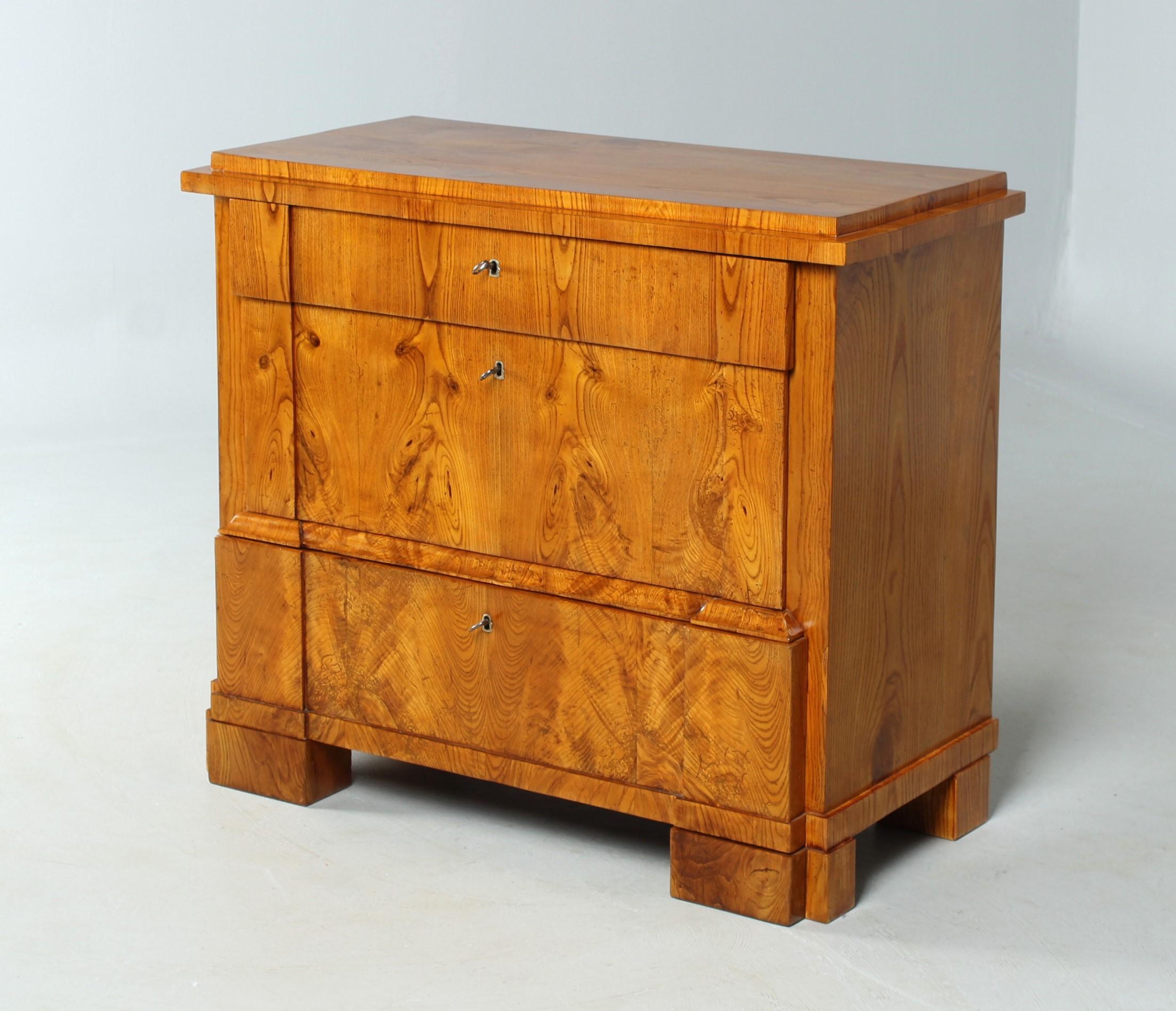 Dimensions: H x W x D: 85 x 97 x 46 cm

Small Biedermeier chest of drawers in ash veneer with typical North German double row of studded feet. Typical for the area are also the drawers protruding to different distances and the distinctive traverse