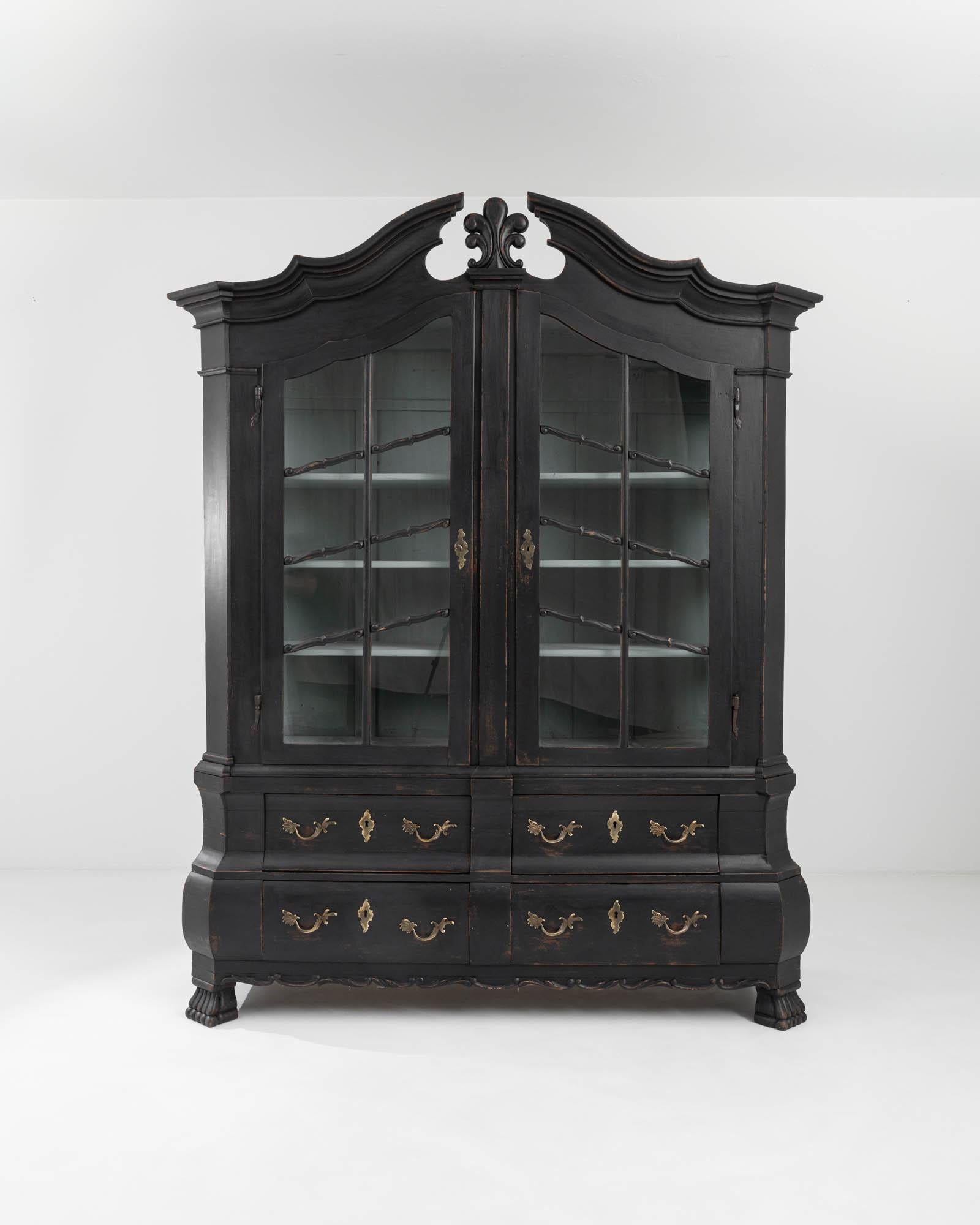 Step back in time and behold the captivating allure of this German vitrine, made circa 1820. This extraordinary piece, massive yet elegantly poised, stands as a behemoth of exquisite craftsmanship, exuding a timeless charm that effortlessly enchants