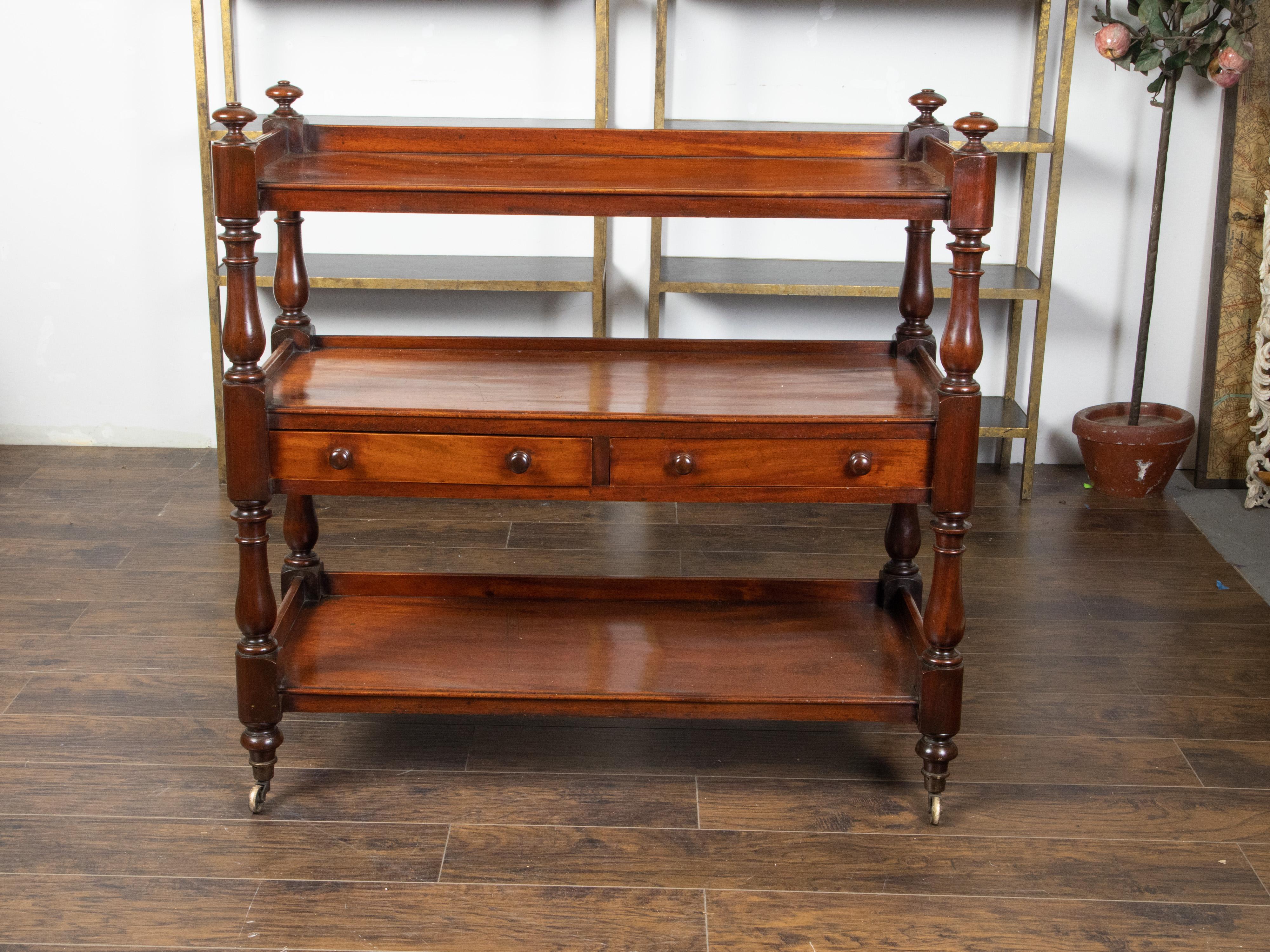 An English mahogany trolley from the early 19th century, with two drawers and brass casters. Created in England during the first quarter of the 19th century, this mahogany trolley features an upper shelf surrounded by a three-quarter gallery