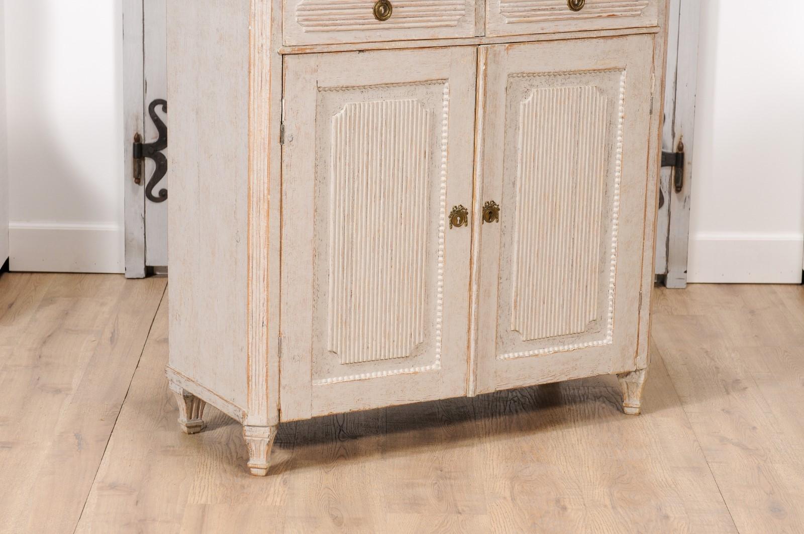 A Swedish Gustavian period painted wood buffet from circa 1820 with two drawers over two doors, carved reeded panels and tapered feet. This exquisite Swedish Gustavian period painted wood buffet from circa 1820, effortlessly marries functionality