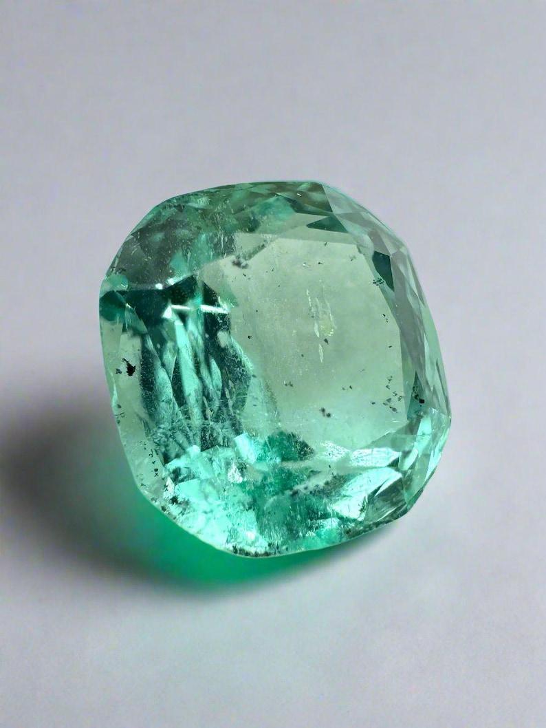 Stone: Emerald
Weight: 1.83-carats
Shape: Cushion Cut
Clarity: Transparent
Luster: Excellent
Color: Light Bluish Green
Measurements: 7.62mm x 7.24mm x 4.99mm
Geographic Origin: Colombia
Treatment: Natural, Oil

Comments: Due to their growth