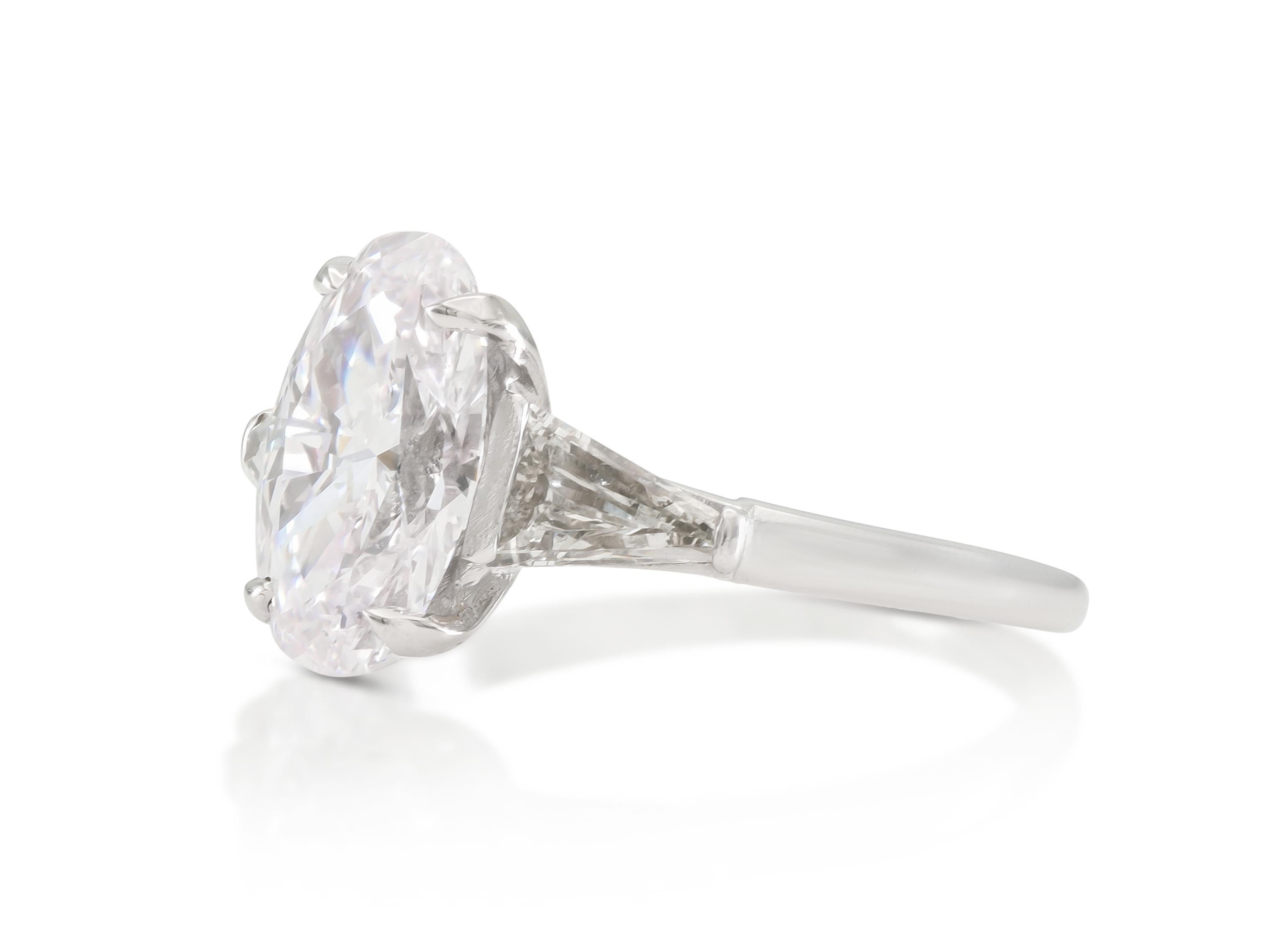 Finely crafted in platinum with a GIA certified Oval cut Diamond weighing 1.83 carats, E color, VVS1 clarity, GIA #1438199879.
The ring features two Tapered Baguette cut Diamonds on the setting.
Size 6, resizable
