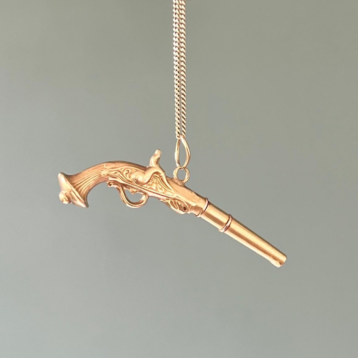 An antique 18 karat yellow gold flintlock revolver pocket watch key pendant from the past. This single-barrel gold flint pistol pocket watch key has a curved lock, floral-carved sides with rococo-style ornaments and a curved carved striped grip.