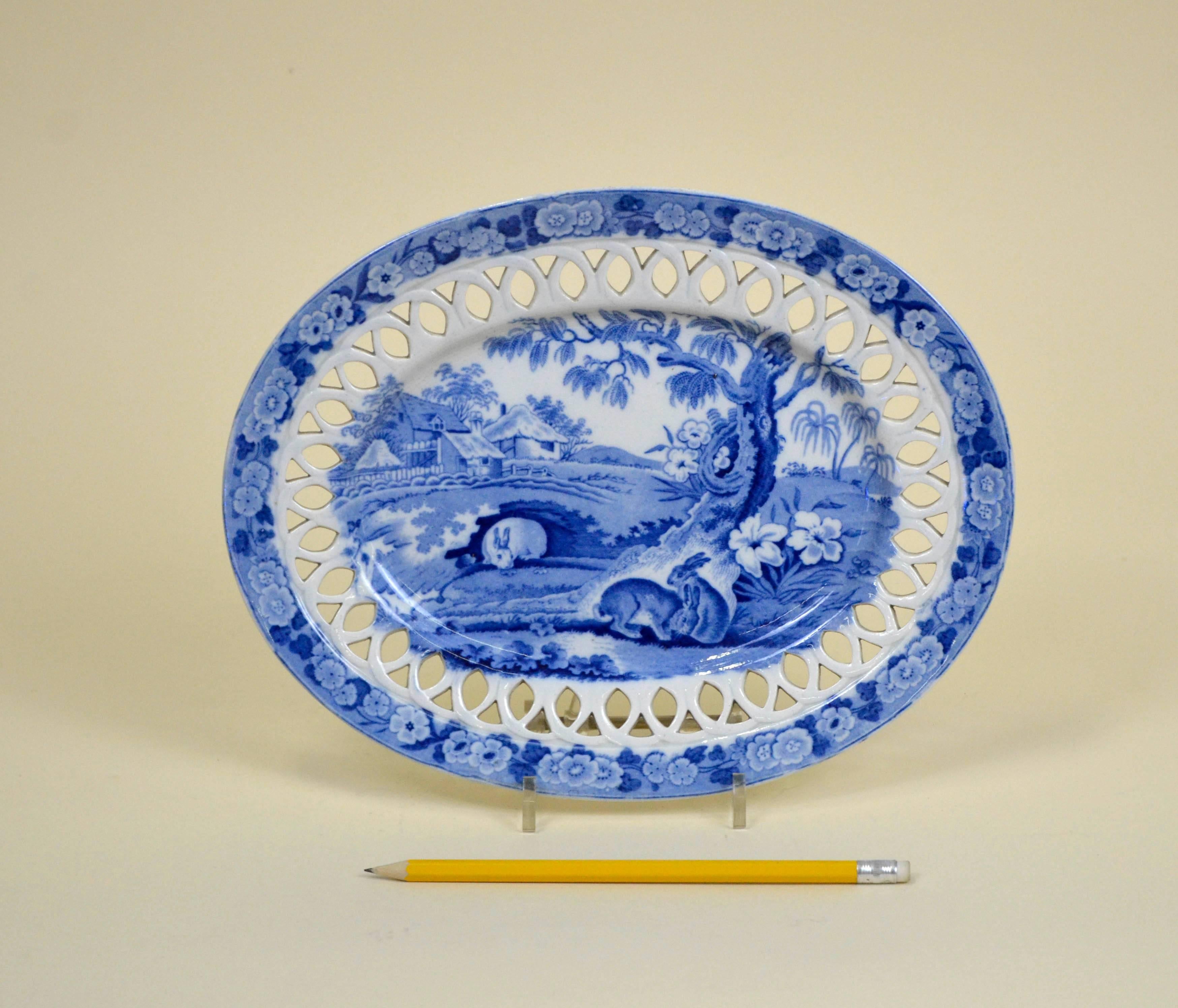 Earthenware oval stand with a basket weaved rim, made in Staffordshire in circa 1830.
Printed in blue and white with grazing rabbits. 

In excellent condition; no chips, cracks, restoration or signs of wear.
 