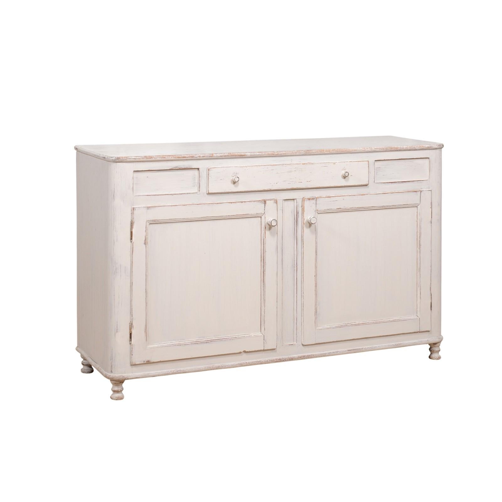 A Swedish grey painted sideboard from circa 1830 with single drawer over two doors. Step into the essence of Swedish elegance with this circa-1830 sideboard, a testament to both function and form. Its soothing grey palette instantly enchants,