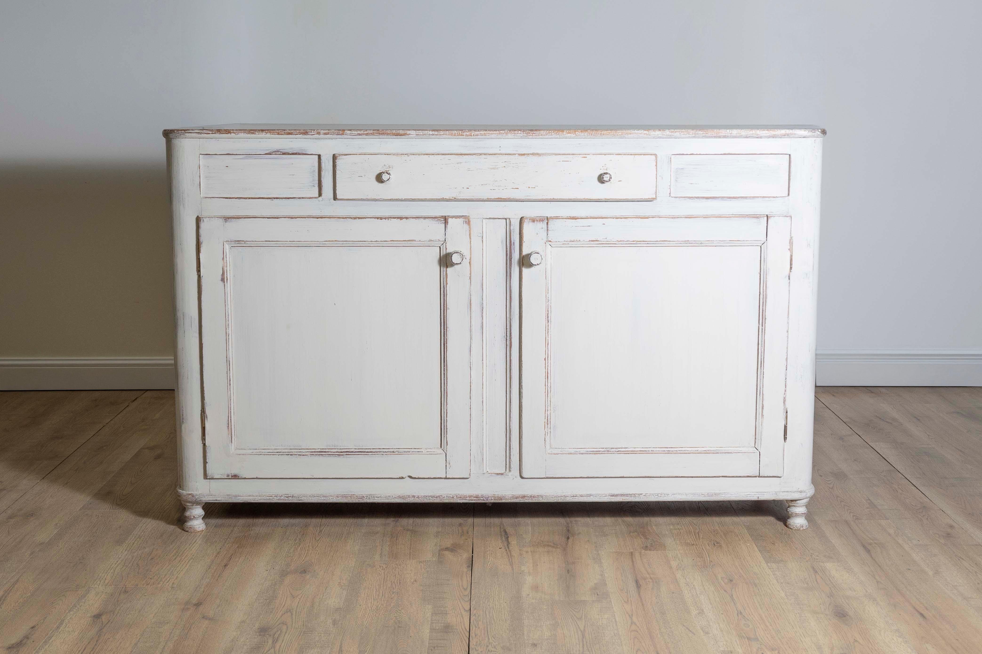A Swedish grey painted sideboard from circa 1830 with single drawer over two doors. Step into the essence of Swedish elegance with this circa-1830 sideboard, a testament to both function and form. Its soothing grey palette instantly enchants,