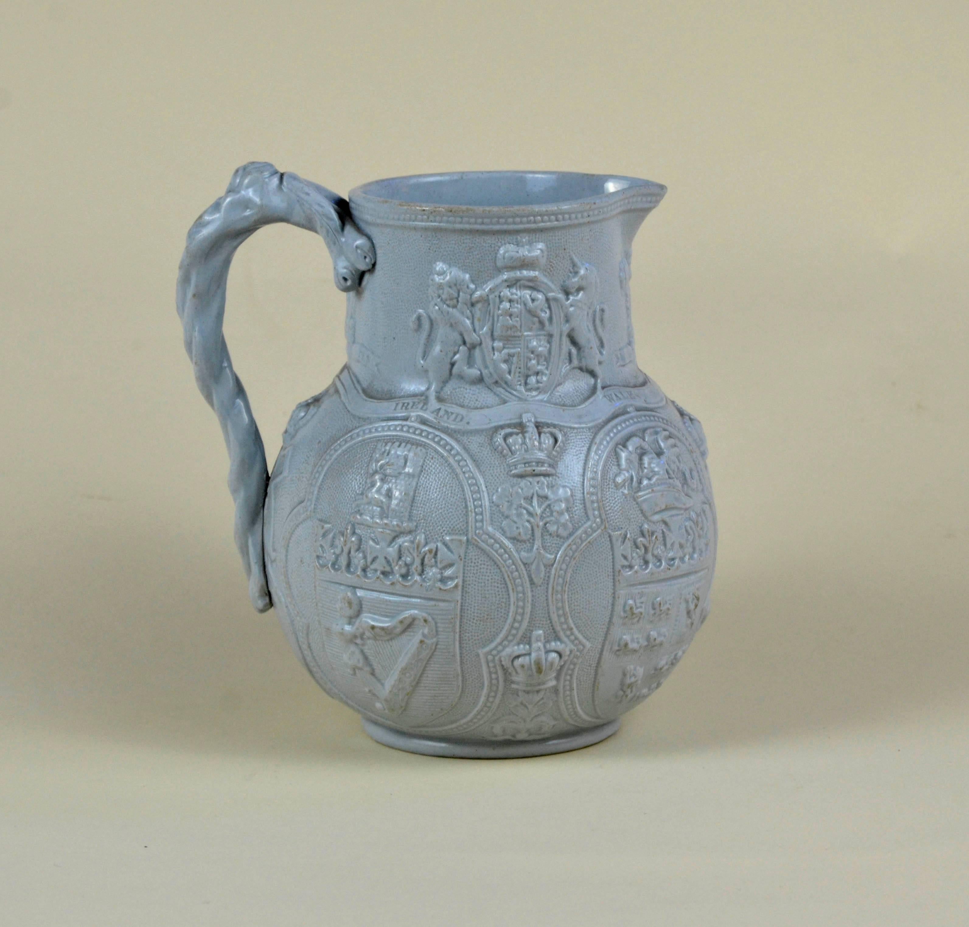 Blue-grey, relief moulded, smear glazed, stoneware jug. Globular body with cylindrical neck and projecting lip, decorated in relief and moulded in two parts. Applied, hand-modelled handle in the form of a twisted branch or vine. On the neck, the