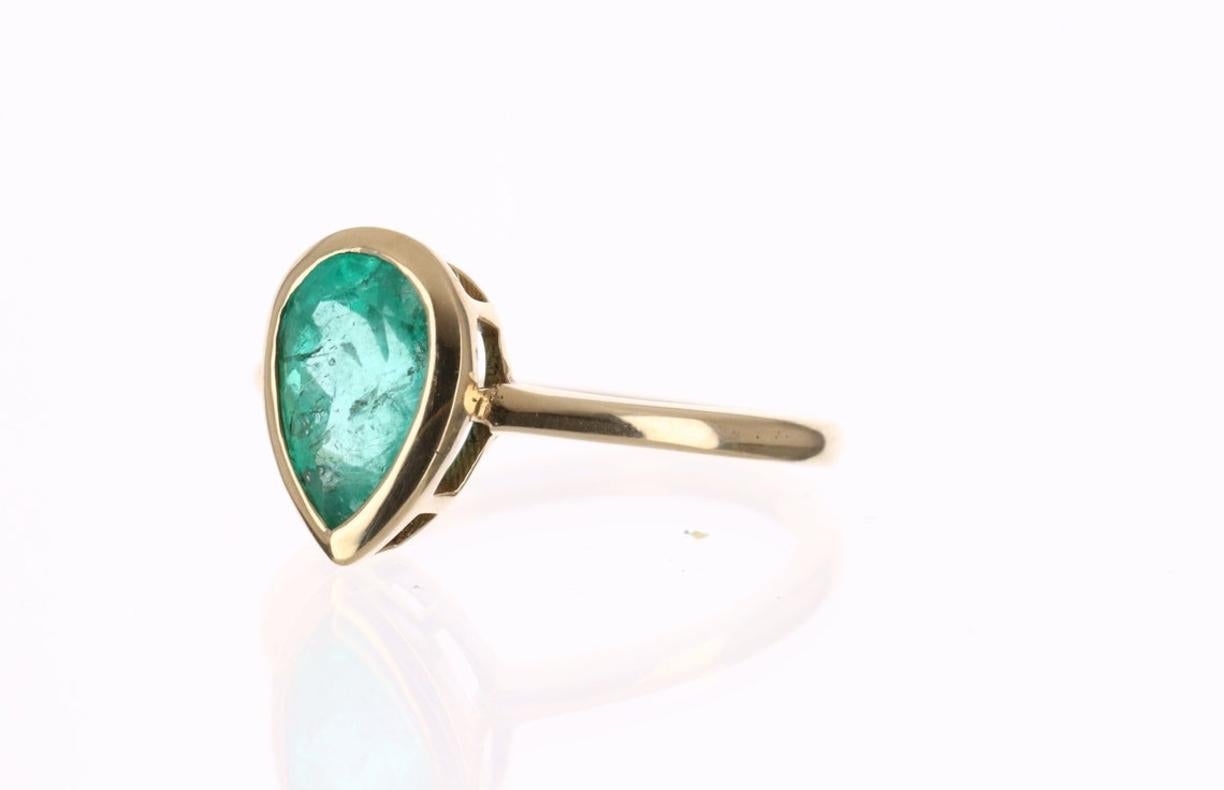 This ring is not for the faint of heart! Displayed is a medium Colombian emerald bezel, teardrop solitaire ring in 14K gold. This gorgeous solitaire ring carries a full 1.83-carat emerald that has incredible flaws that will have you dazing into its