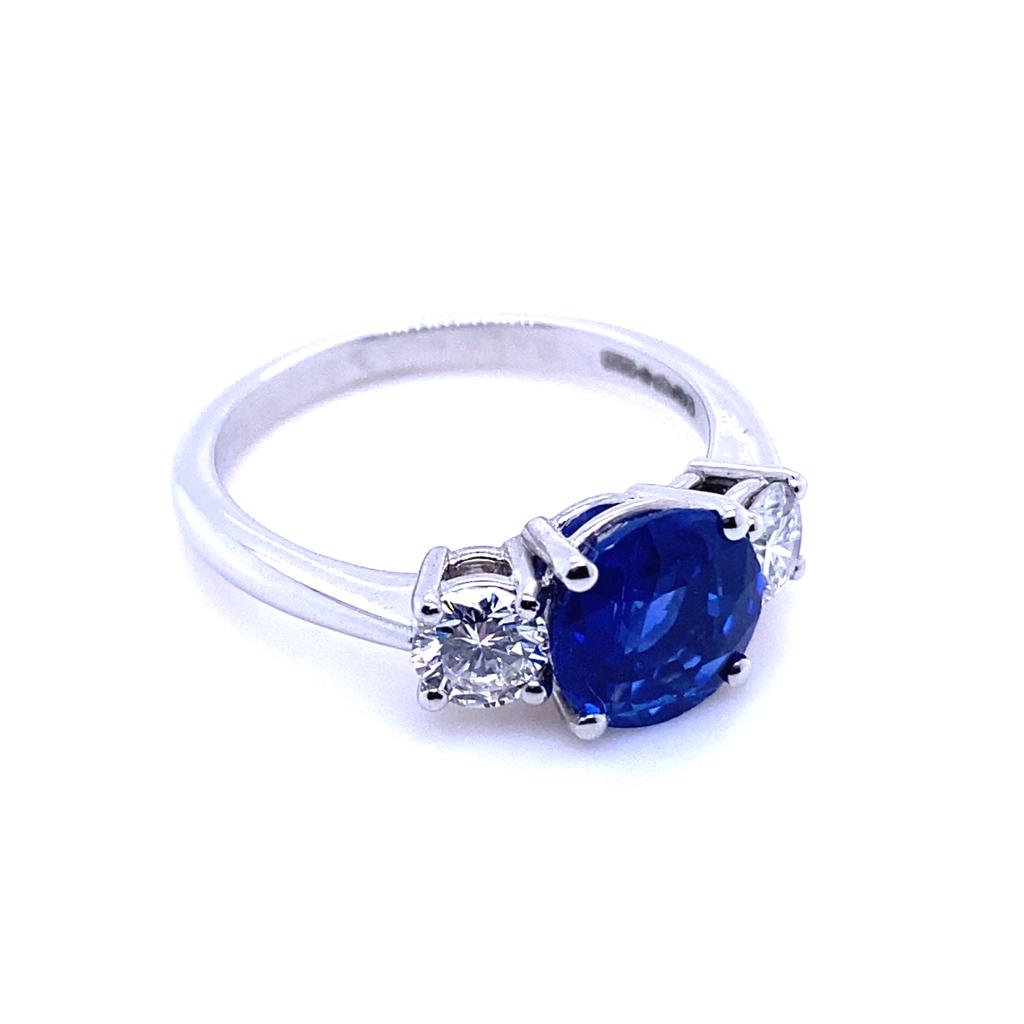 An 1.84 carat Kashmir sapphire and diamond three stone platinum engagement ring.

This exceptional sapphire and diamond engagement ring is handcrafted in platinum.  
Claw set to its centre with a round cut sapphire of 1.84 carats. The stone is a