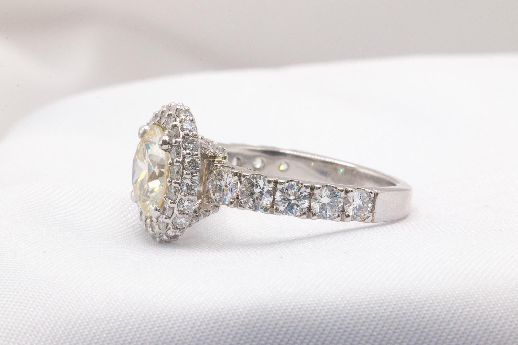 This exquisite platinum ring features a 1.84-carat natural round brilliant diamond, graded N color and VS2 clarity, enhanced by a sparkling diamond halo for added brilliance. Accompanied by its original GIA certificate (#6233428623), the centerpiece