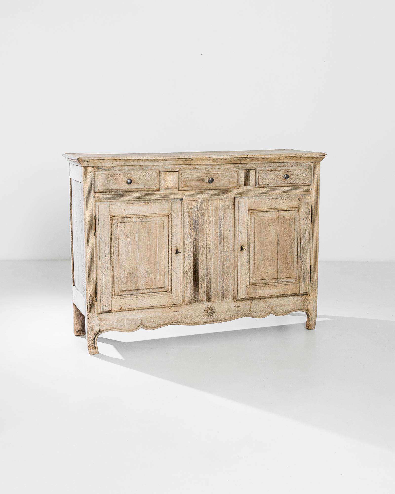 Lively decorative accents give this antique oak buffet a refined charm. Made in France in the 1840s, the panels of the upright case are caved with fluted detail and mermaid scales; a carved rosette hangs in the curves of the scalloped apron. The oak