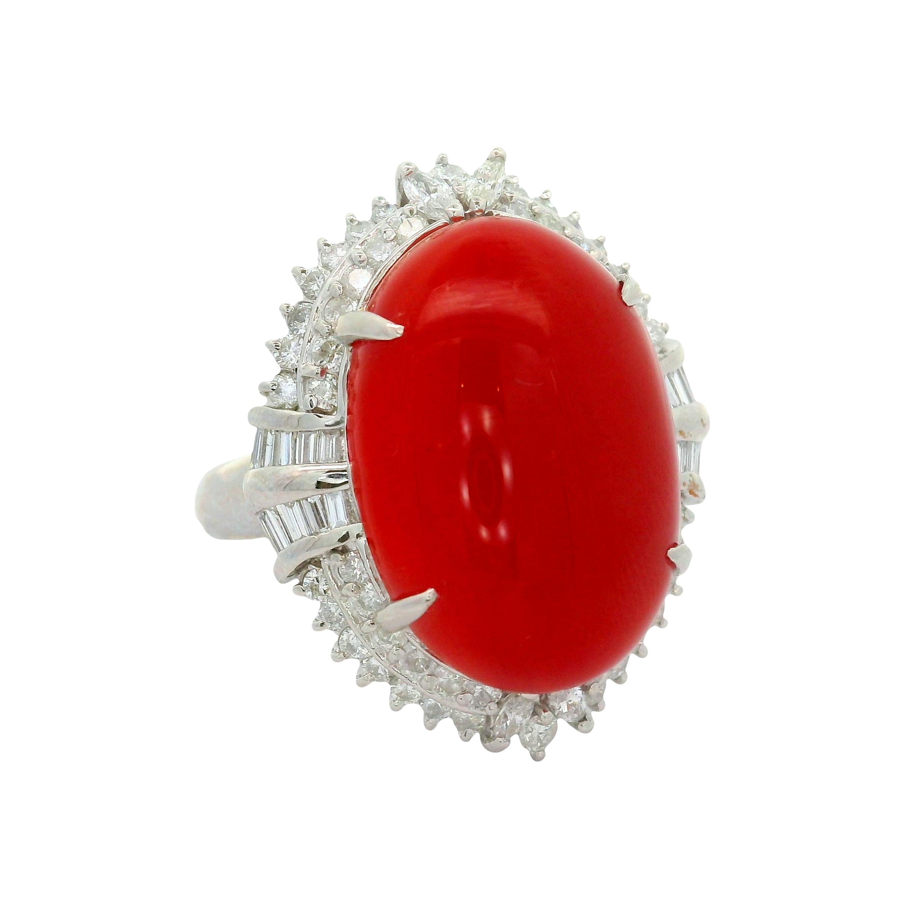 Bold elegance. This cocktail ring features an 18.43-carat cabochon coral, radiating a deep red hue and known in the trade as ox-blood for the finest color coral. It is encircled by 1.48 carats of mixed-cut diamonds, offering a striking white