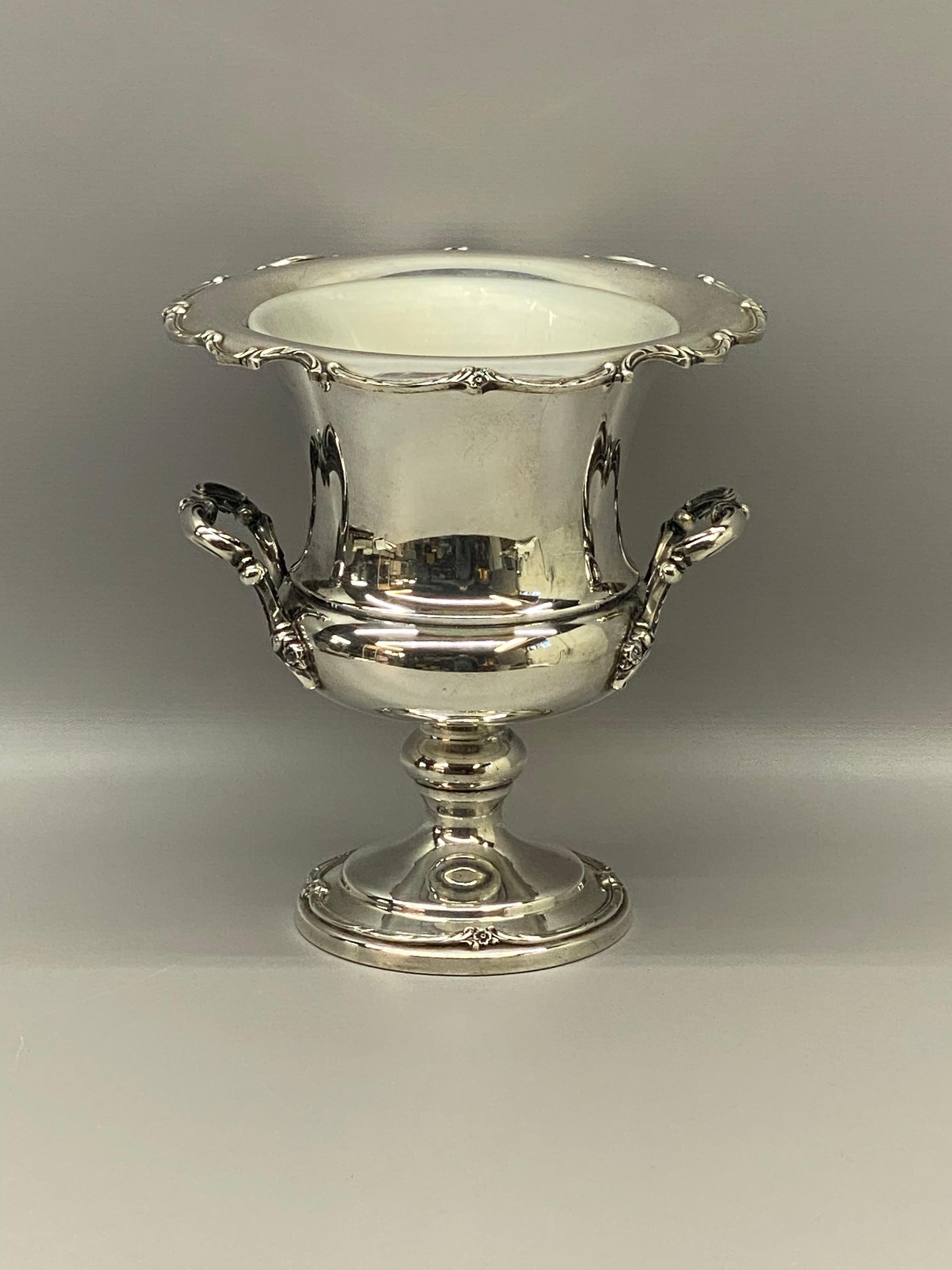 Beautiful and refined Rogers silver-plate champagne cooler. Signed on the bottom, Reflection, 1847 Rogers Bros. IS, 9250. Decorated in a raised floral garland design on the handles, lip and base. Scalloped edge. It still retains its removable