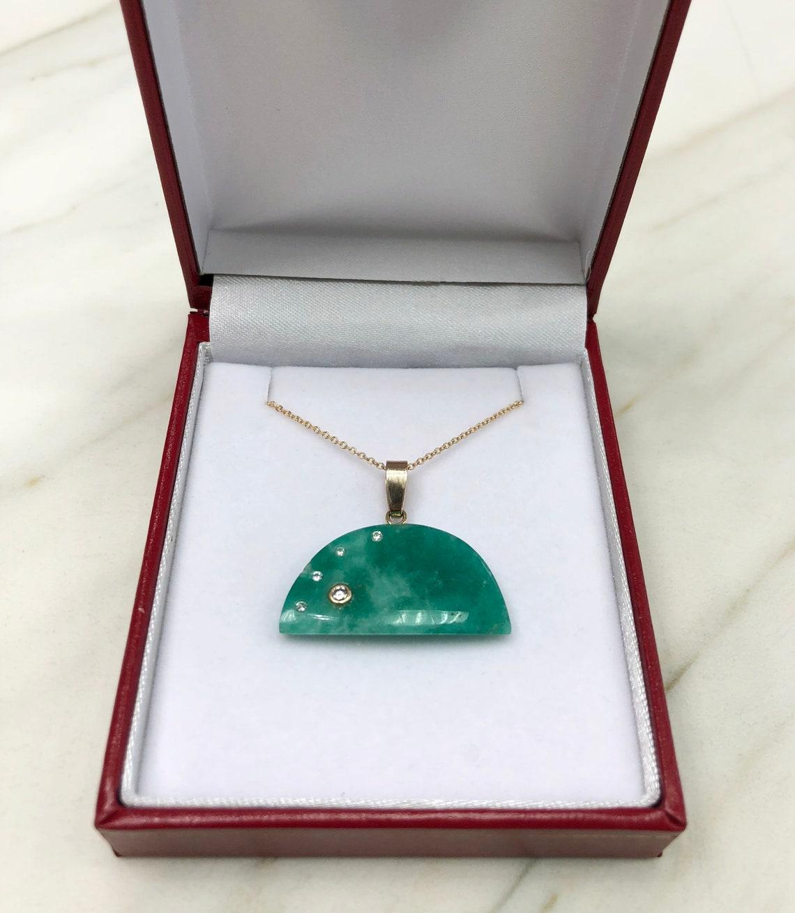 Displayed is our most unique, handcrafted yet so simple piece, made of a solid Colombian emerald stone and diamonds. A natural, emerald slab is encrusted by brilliant round diamonds, accented with a 14k gold bale. The emerald is earth mined and