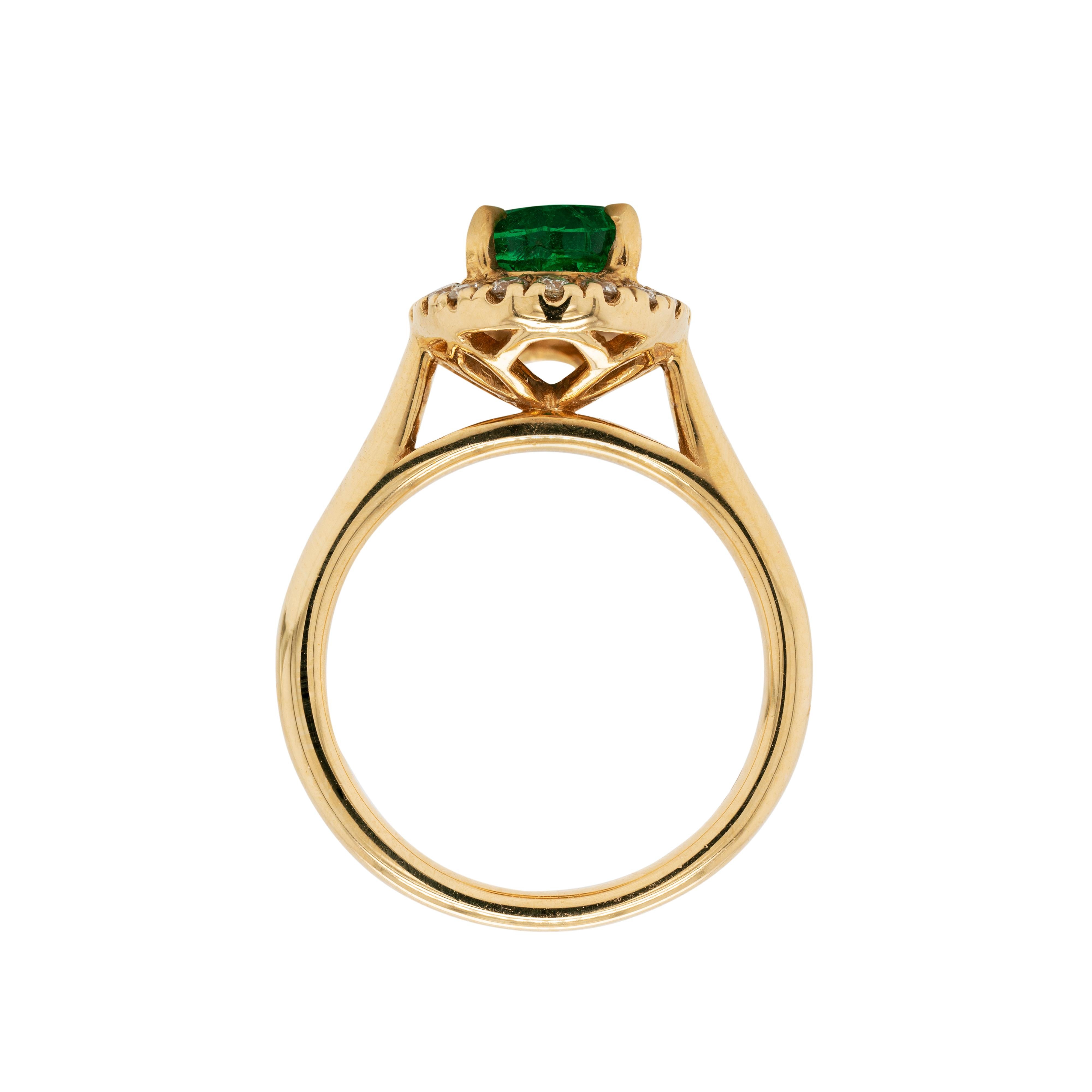 This gorgeous 18 carat yellow gold cluster engagement ring features a 1.85ct oval shaped emerald, in an open back, four claw setting. The vibrant gemstone is surrounded by an exquisite halo of eighteen claw set fine quality round brilliant cut