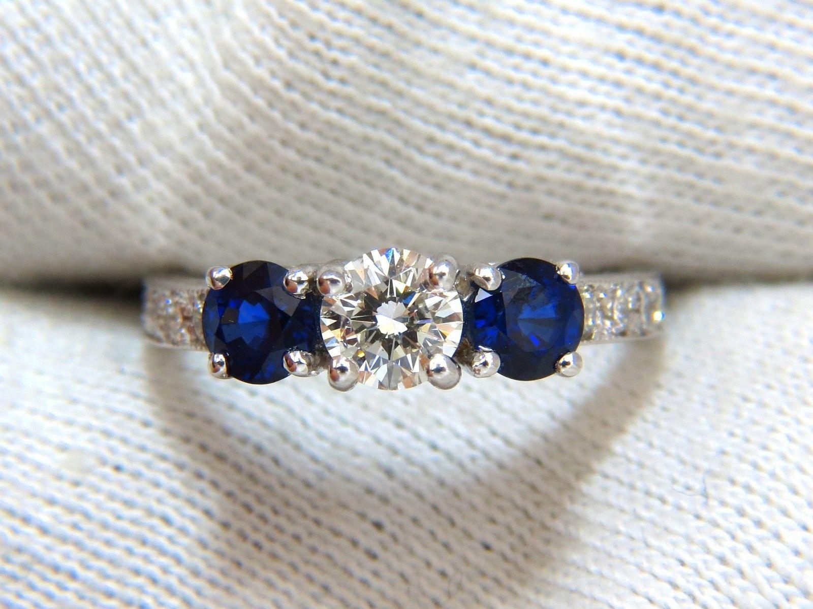 Ladies round shaped sapphires ring, three stone classic

.50ct. Center Diamond.

Round, Full cut Brilliant

5.1mm diameter

I-color Si-1 clarity.

1.00ct. Natural (2) Blue Sapphires

Vivid Blue colors, clean clarity & Transparent.

Full cut round