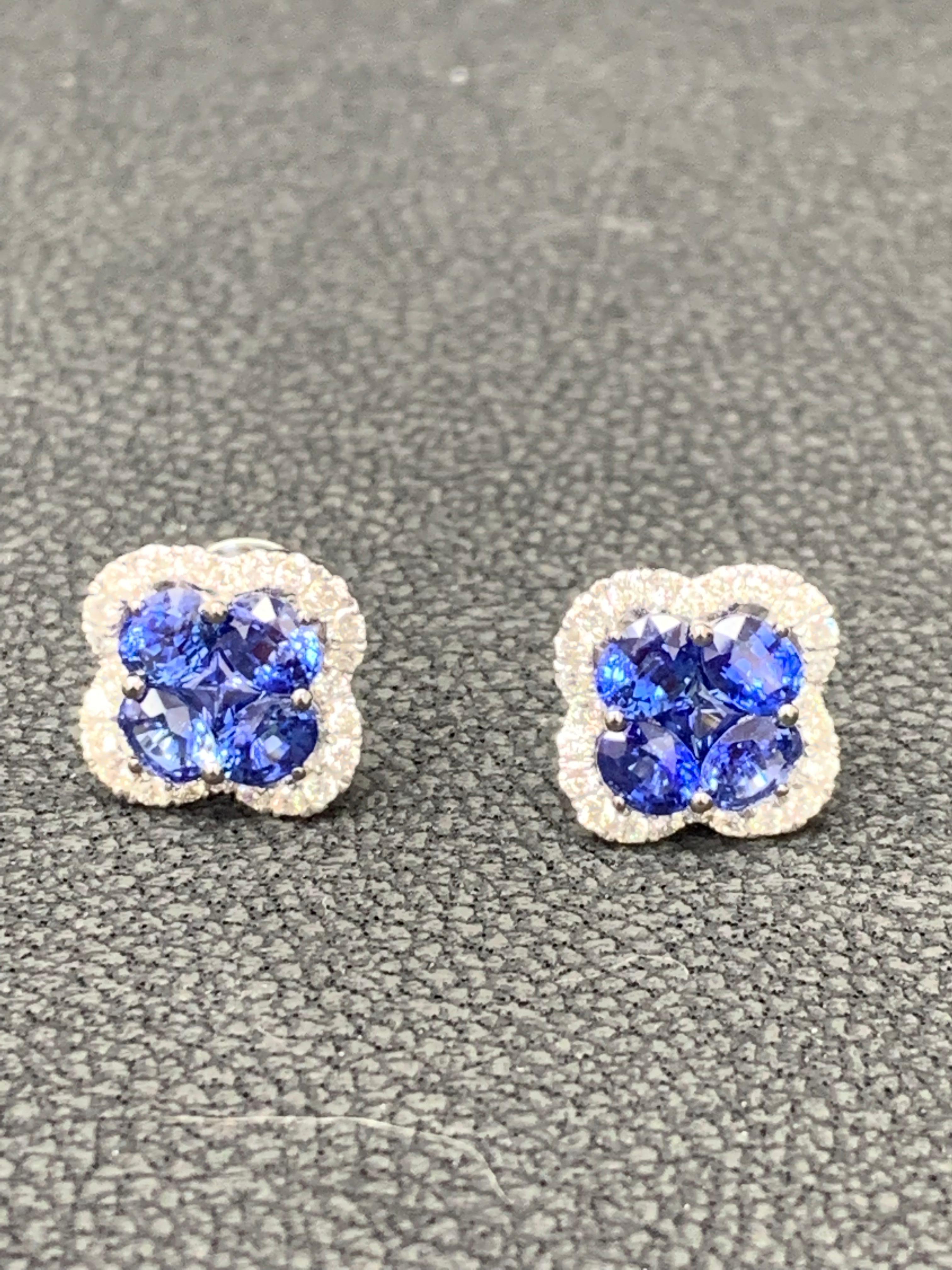 Showcasing flower design stud earrings with 8 oval shape Blue Sapphires weighing 1.85 carats total and 2 round shape Blue Sapphires weighing 0.17 carat, accented by a row of round brilliant diamonds. Diamonds weigh 0.40 carats total. Set in a