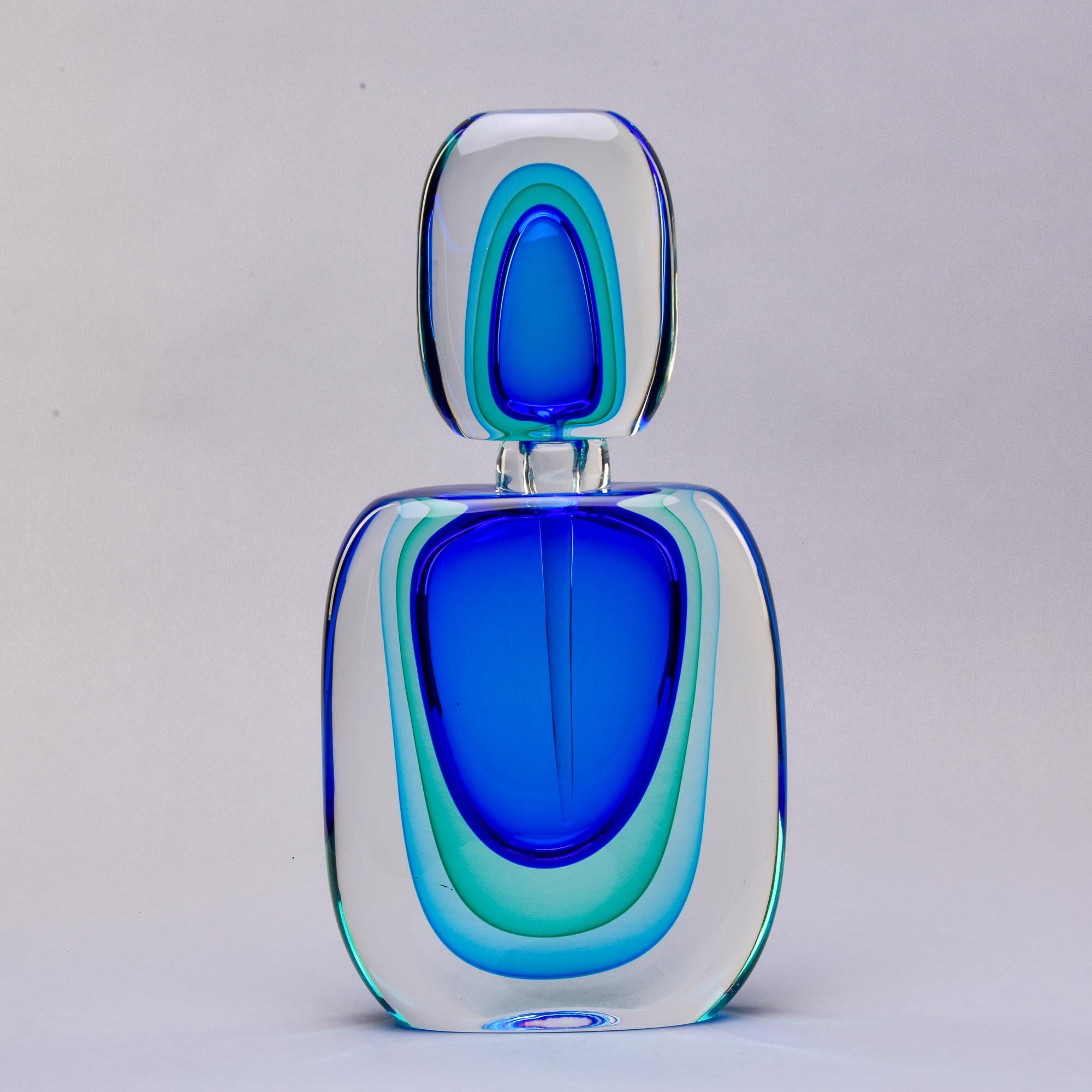 New oversized Murano glass perfume bottle stands 18.5” tall. Done in sommerso style with layers of blue and green toned glass submerged in heavy clear glass. Coordinated stopper has an attached scent dabber. Unsigned - unknown Murano maker. At the