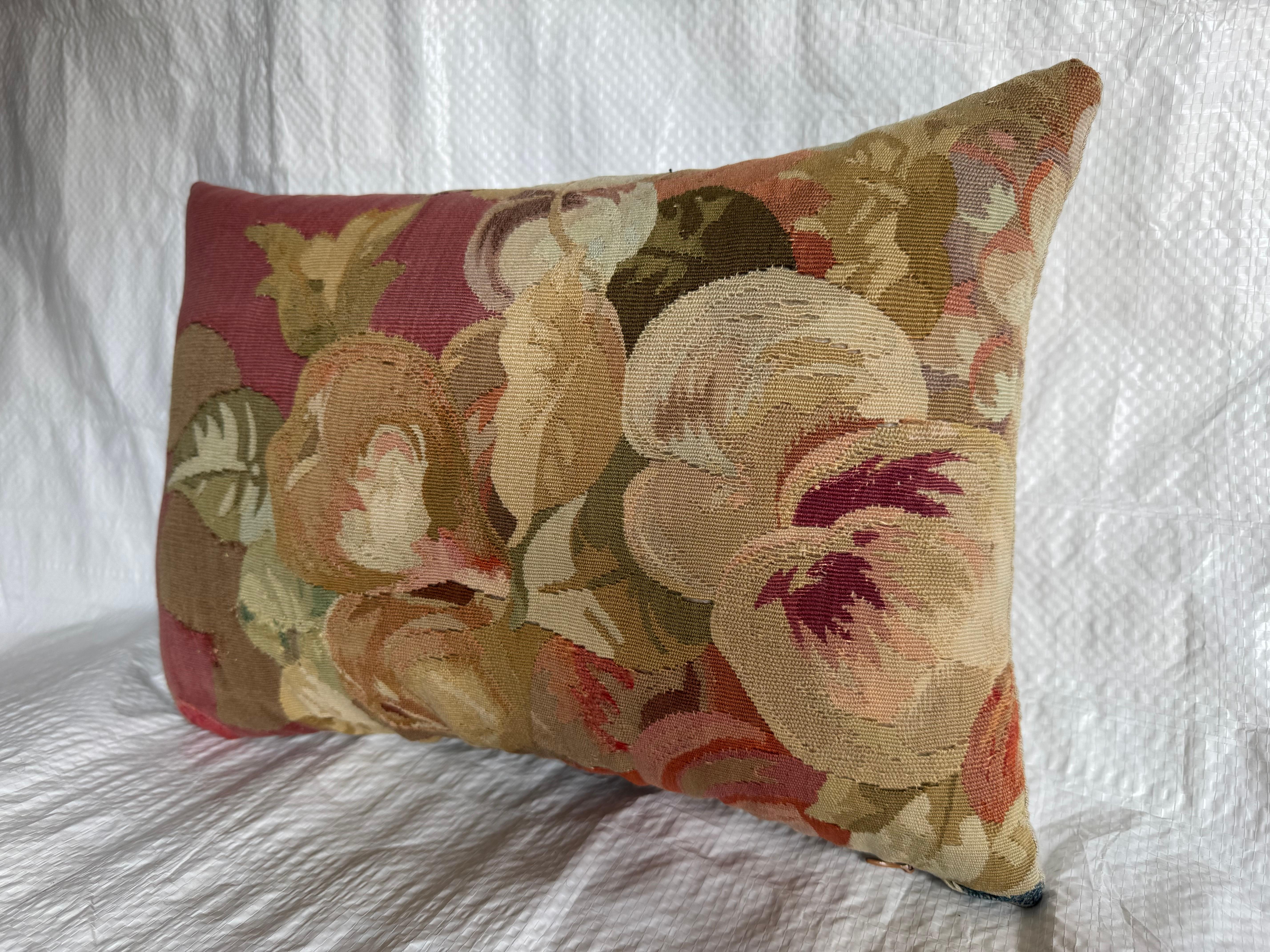Questo cuscino è ricavato da un frammento di arazzo Aubusson del XIX secolo, risalente al 1850 circa. Mostra una lussureggiante composizione floreale intrecciata nei toni del blush, dell'avorio, del verde e dell'ocra tenue, accentuata da un campo