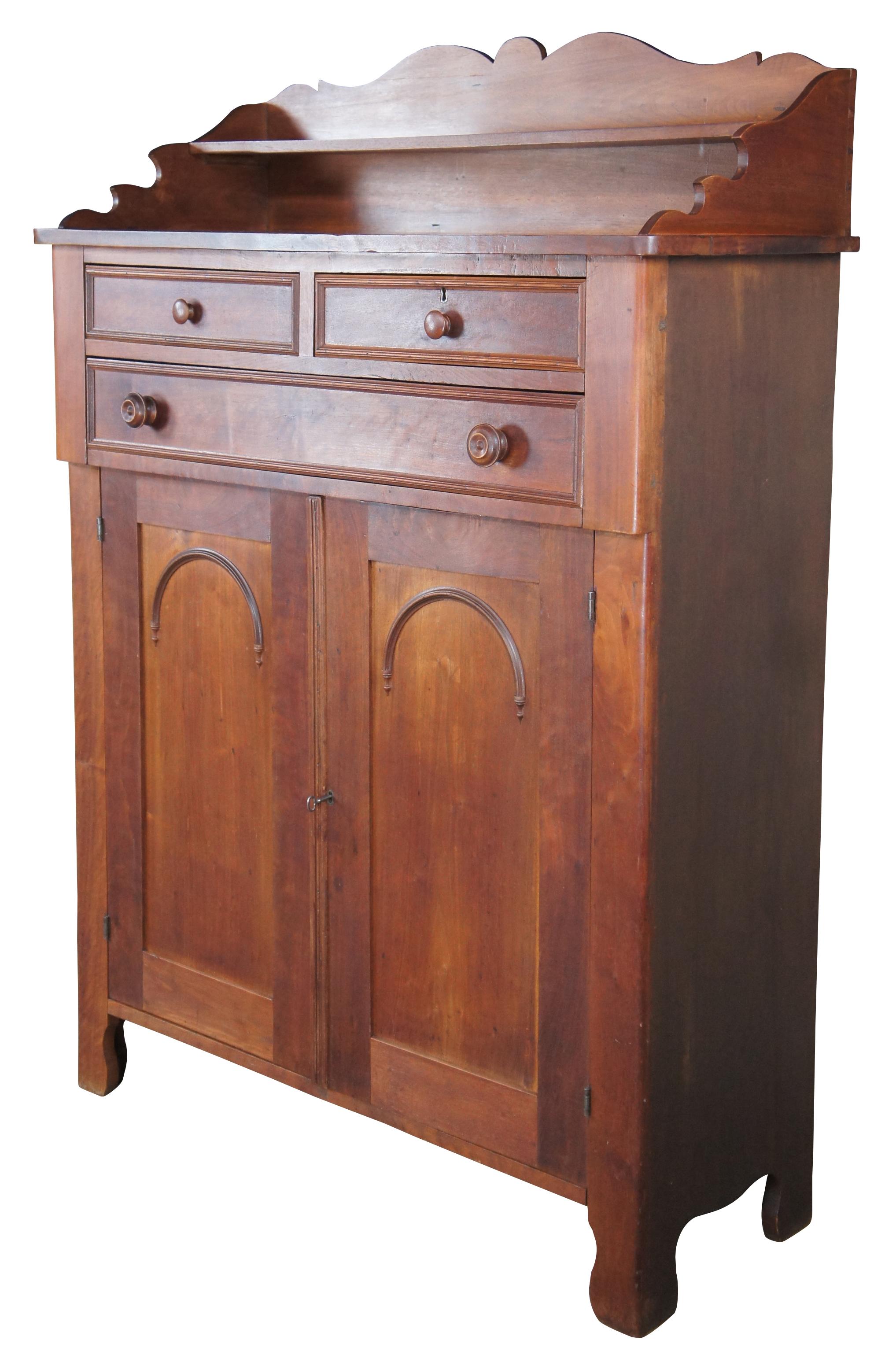A warming handmade mid 19th century Early American jelly cabinet or pantry cupboard. A rectangular form made from American Walnut with an upper surface enclosed by a serpentine backsplash that features one shelf, over three hand dovetailed drawers