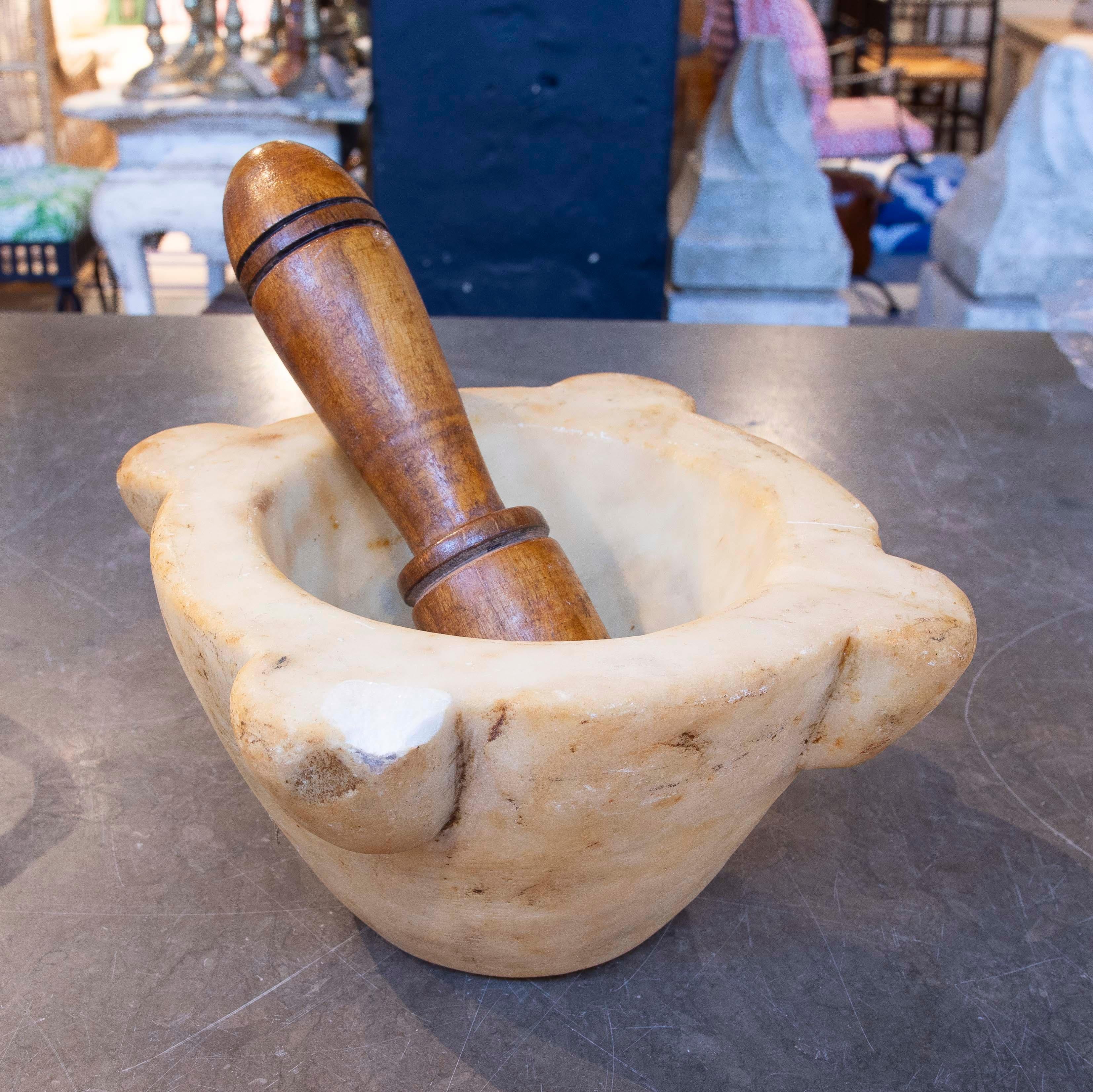 Mortaio e pestello tradizionale ricavato da un unico pezzo di marmo bianco con venature naturali e usura che ne riflettono l'uso e l'età. Presenta quattro robusti manici laterali e una forma profonda e affusolata ideale per macinare gli ingredienti.