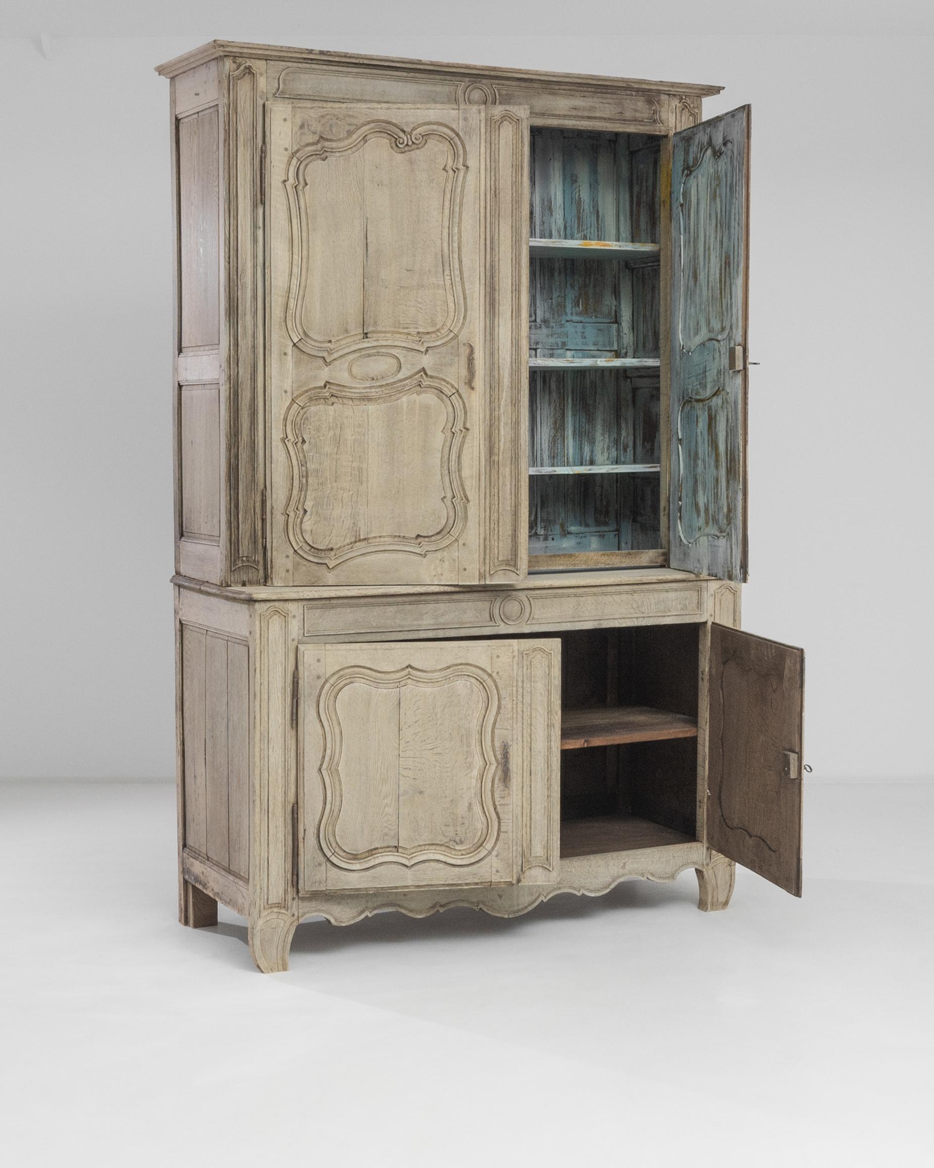 The ashen hue of the bleached oak accentuates the grandeur of this vintage buffet ‘a deux corps’ handcrafted in France circa 1850. Crowned with a molded cornice, this chest boasts deep curvilinear carvings of the panel doors echoed in the waves of