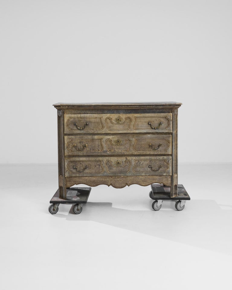 The fluid contours of the panelling and silky taupe color of the oak give this antique chest of drawers a unique appeal. Made in France in the 1850s, the scrolls and billows of the drawer panels lend a Baroque inflection to the upright shape.