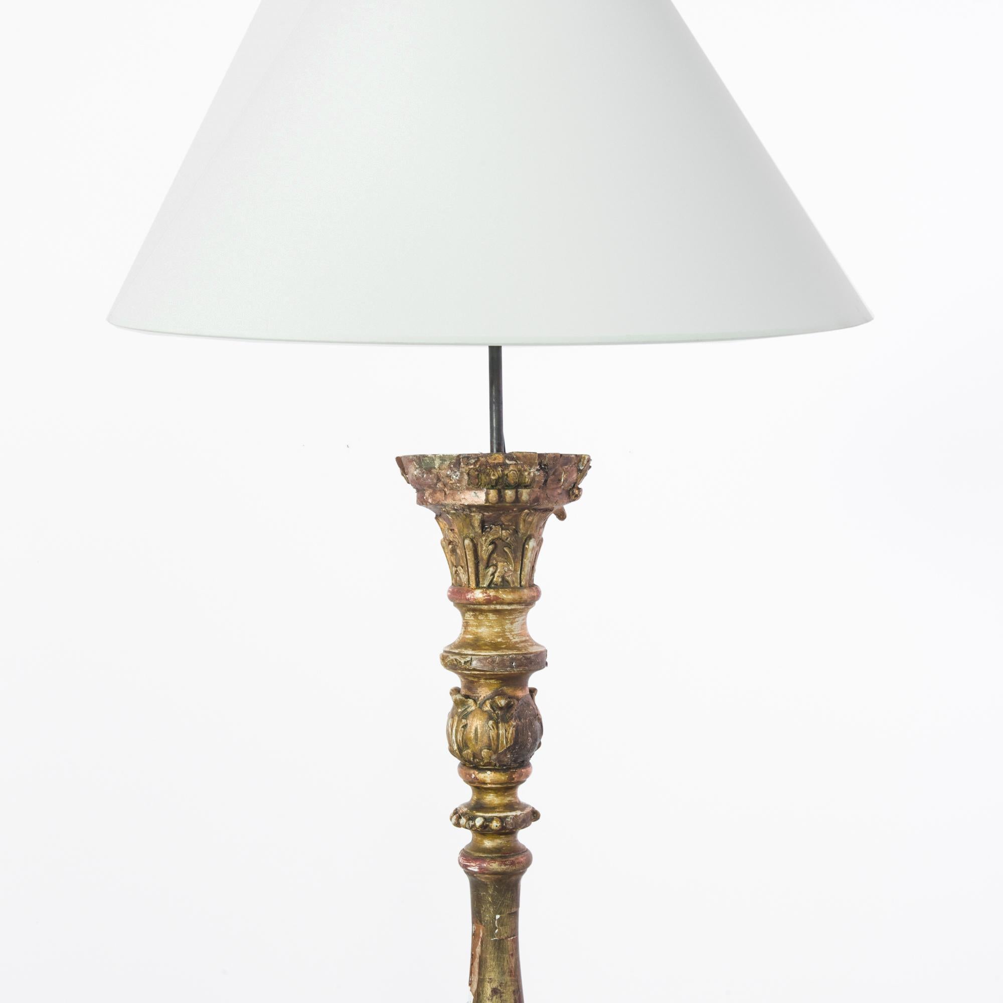 A wood patinated floor lamp produced in France circa 1850. A gilded stalk, covered in bountiful leaf carvings, standing on three toes, rises to a height of six and a half feet capped by a white lamp shade. This striking antique is sure to enshrine