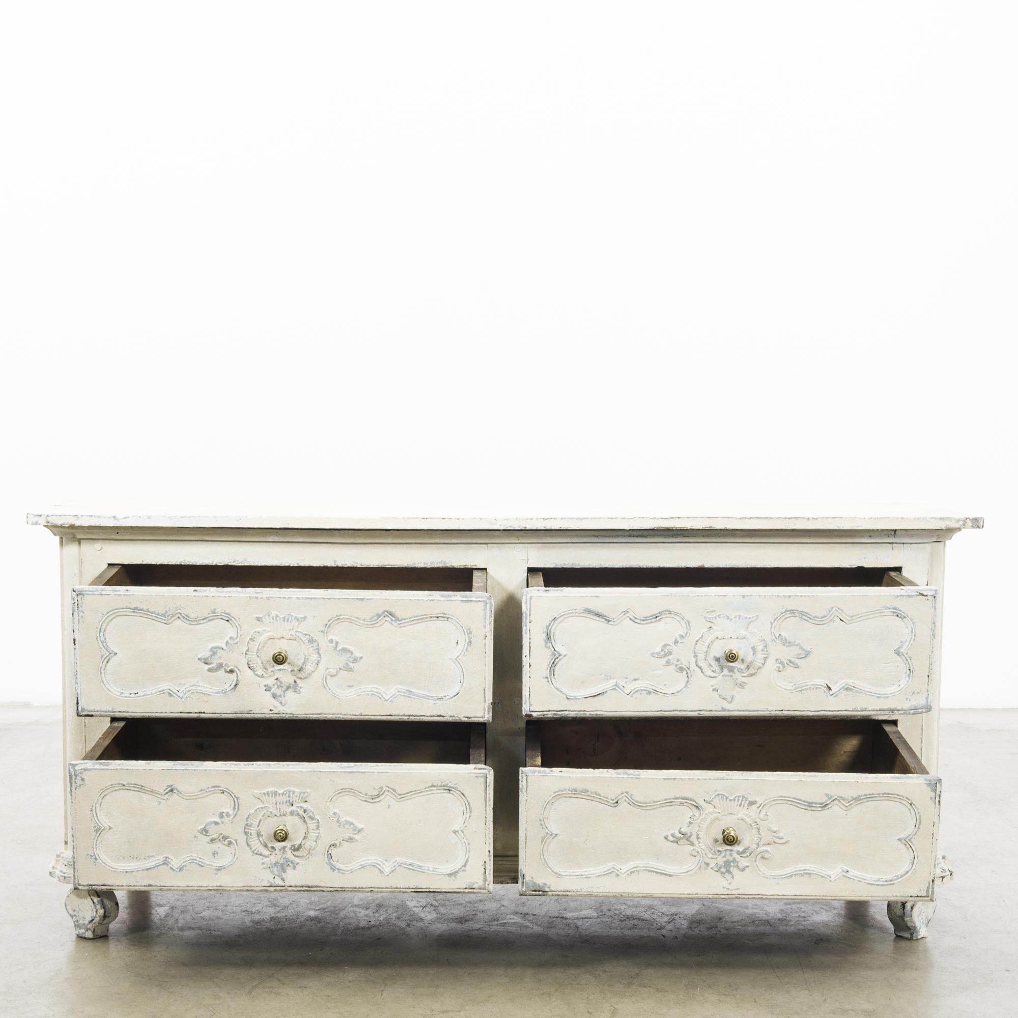 Step back into the romantic era of the 1850s with this French wooden chest of drawers, adorned with a white patina that tells a story of time's passage. Each drawer features intricate, hand-carved detailing, accentuating its vintage charm and