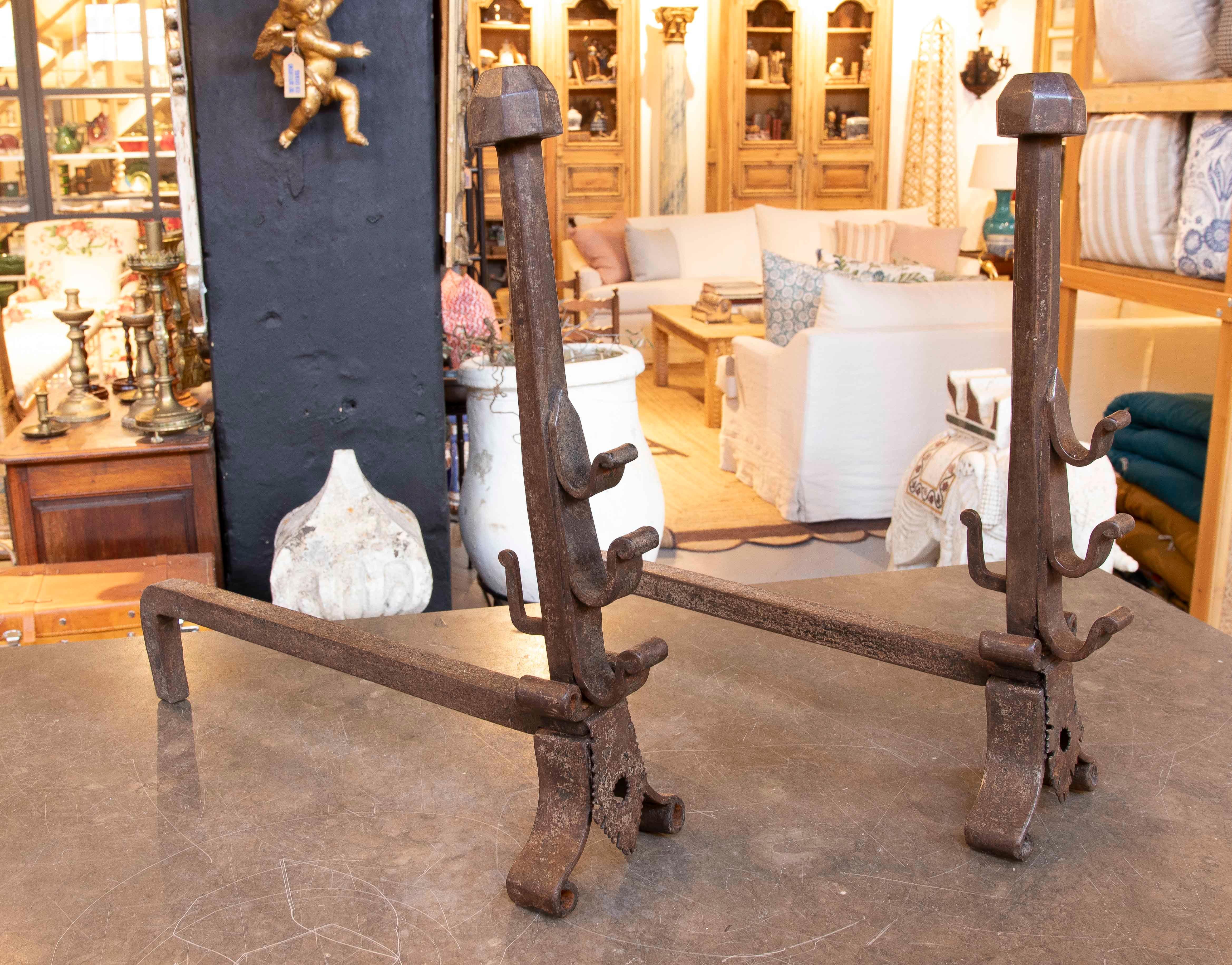 Coppia di morilli in ferro battuto con design classico e dettagli decorativi. Questi accessori per caminetti sono dotati di supporti regolabili per accogliere ceppi di diverse dimensioni e garantire una combustione uniforme. La loro struttura