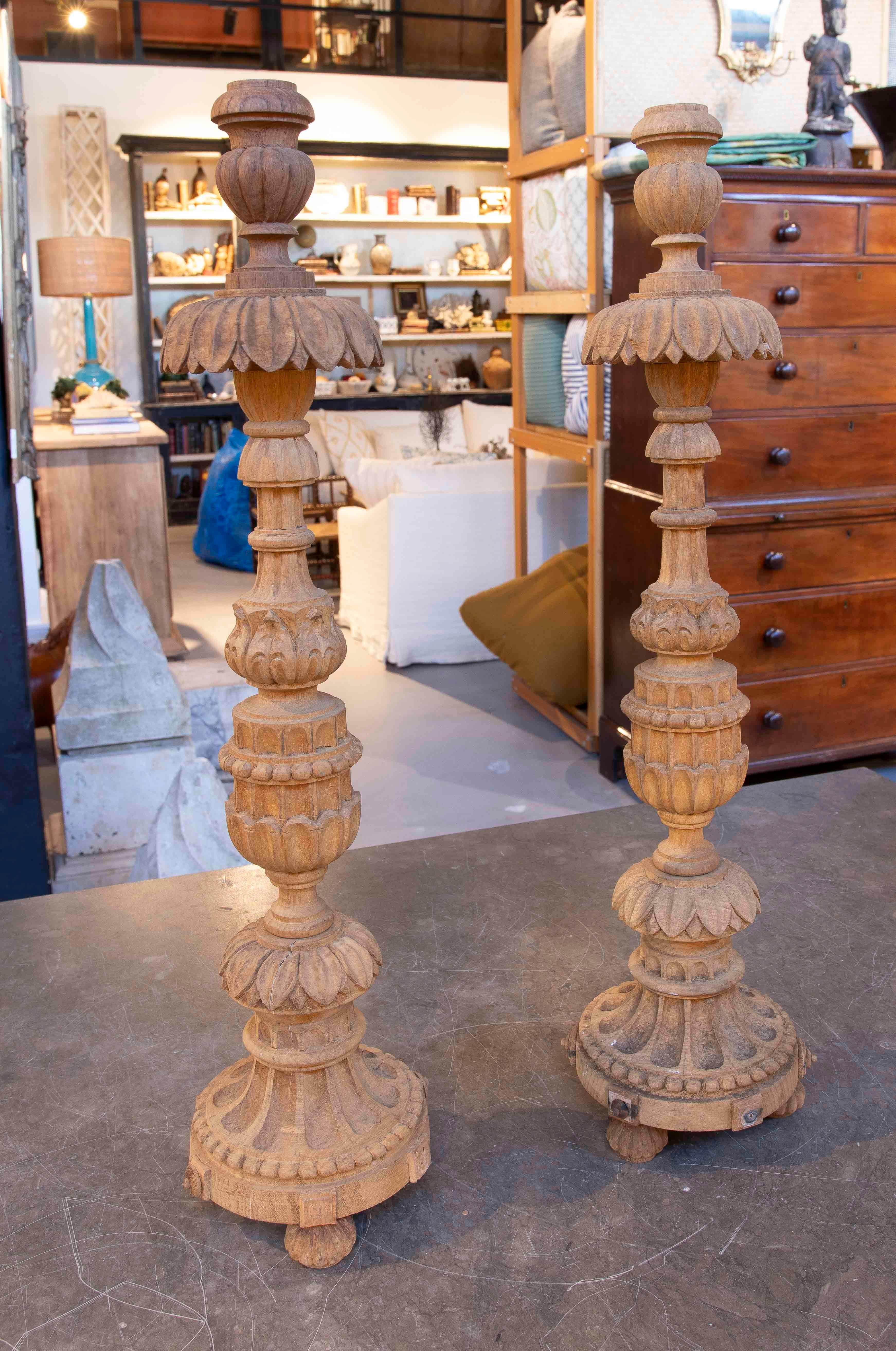 An impressive pair of Baroque-style candlesticks carved from solid wood, featuring a richly decorated design featuring striations, plant motifs, and pearl borders. Their natural, unvarnished finish reveals the wood's original texture. Each