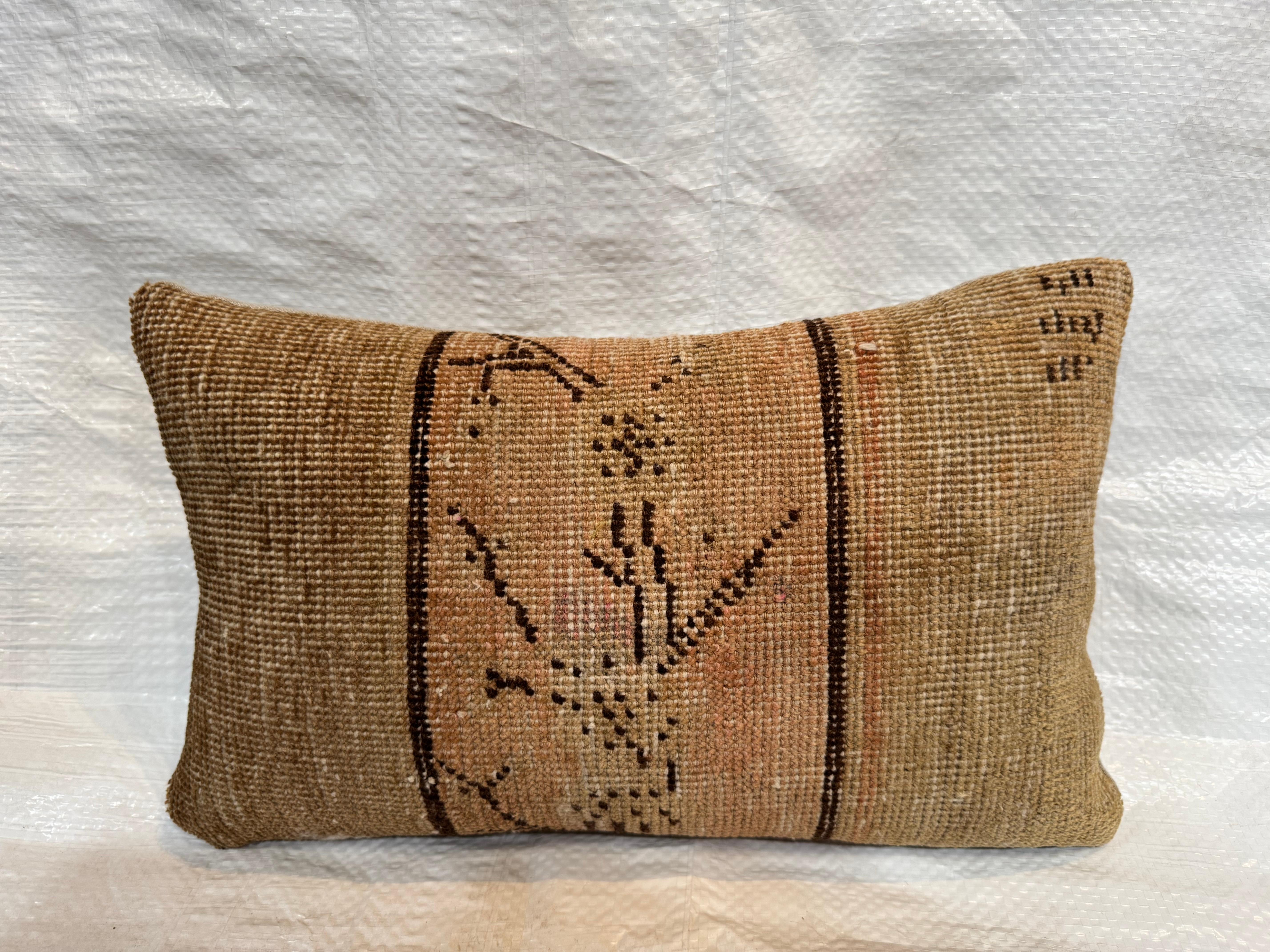 This striking decorative pillow is made from a rare 19th century Samarkand rug fragment, woven in Central Asia around the 1850s. The design is rooted in tribal traditions, featuring a bold, linear motif in a balanced, minimal composition. Faded hues