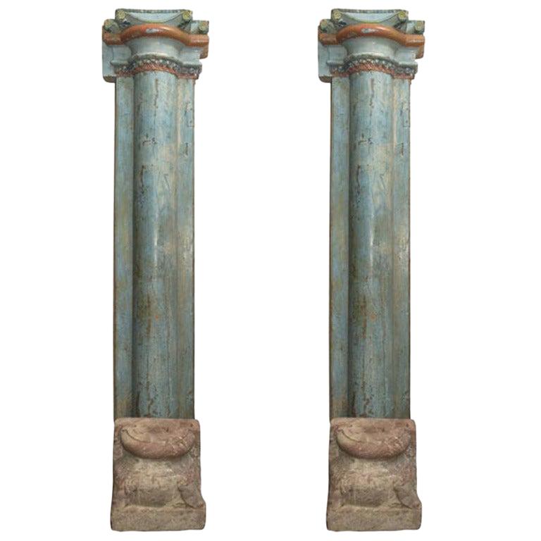 1850s French carved and painted wooden columns with decorative stone bases. A unique pair of statement-making architectural accents, the aged aquamarine paint with crimson, blue and green detailing gives these columns an old-world, romantic appeal.