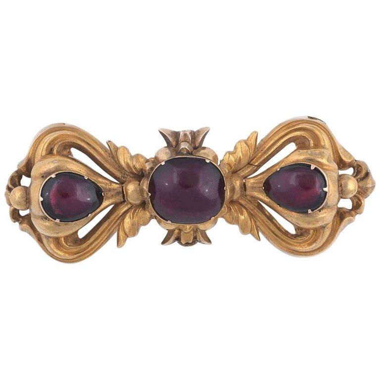 
Chased throughout with a scrolling floral and acanthus leaf design, centered by collet set almandine cushion cut garnet with two drop cut other almandine garnets.

Mounted in yellow gold

Length 5.3 cm

Weight: 8 gr