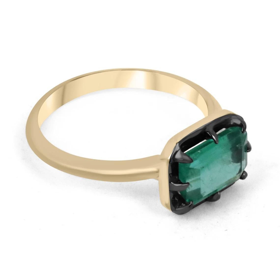 Displayed is a one-of-a-kind, natural emerald solitaire emerald-cut engagement ring/right-hand ring in 14K yellow gold, with a black rhodium rim over the bezel. This gorgeous solitaire ring carries a full 1.85-carat Zambian emerald in an eight-prong