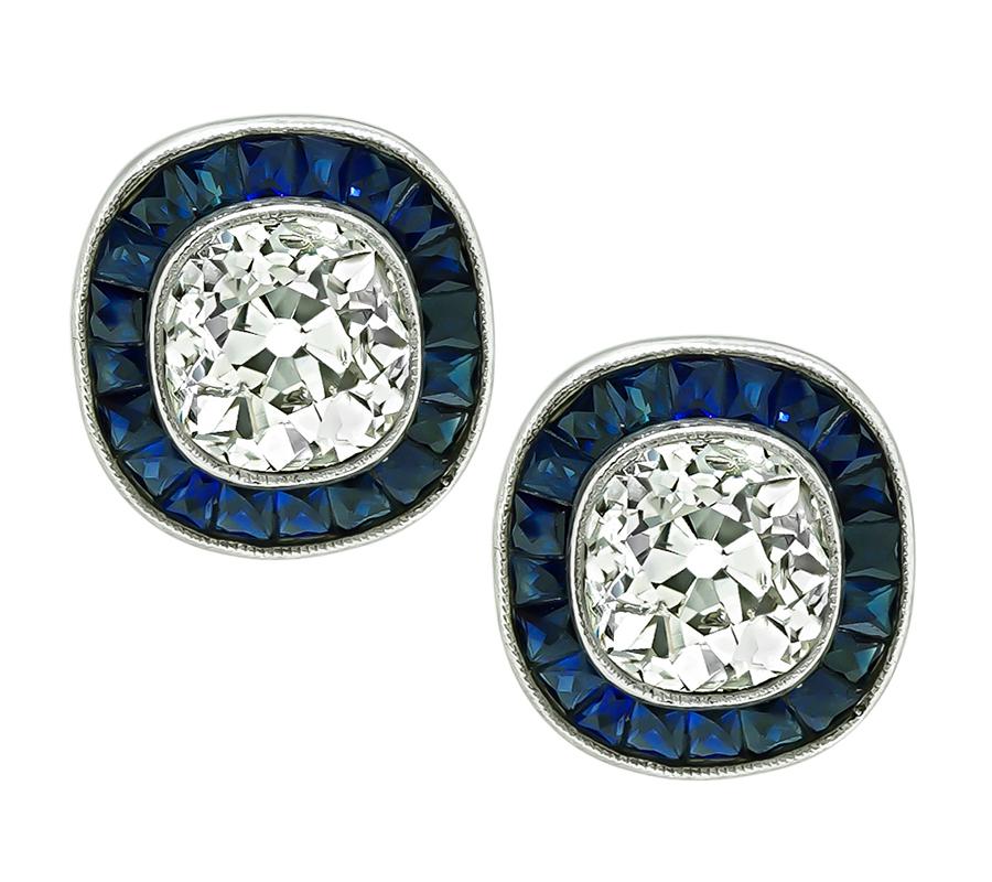 This is an amazing pair of platinum stud earrings. The earrings feature sparkling cushion cut diamonds that weigh approximately 1.85ct. The color of these diamonds is H-I with SI2 clarity. The diamonds are accentuated by lovely French cut sapphires