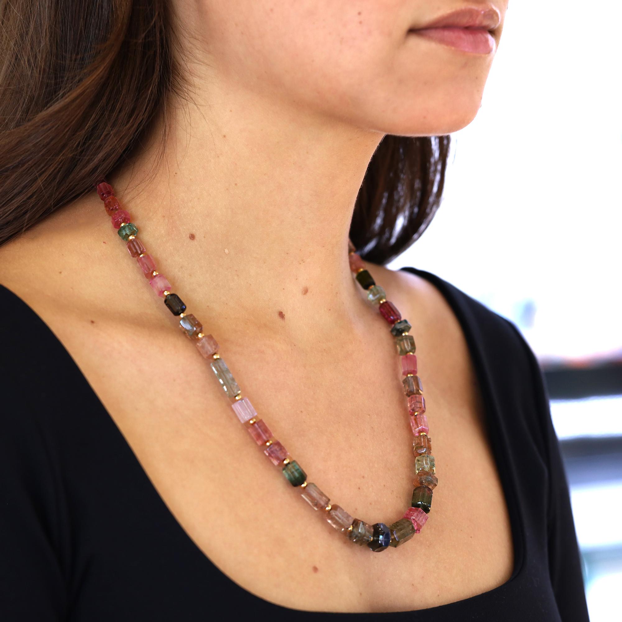 A lovely, multi colored natural tourmaline bead necklace. The strand composed of 51 organic, raw looking faceted gemstones weighing 186 carats is strung with 14k yellow gold spacers and completed by a two tone diamond-accented ball clasp. The colors